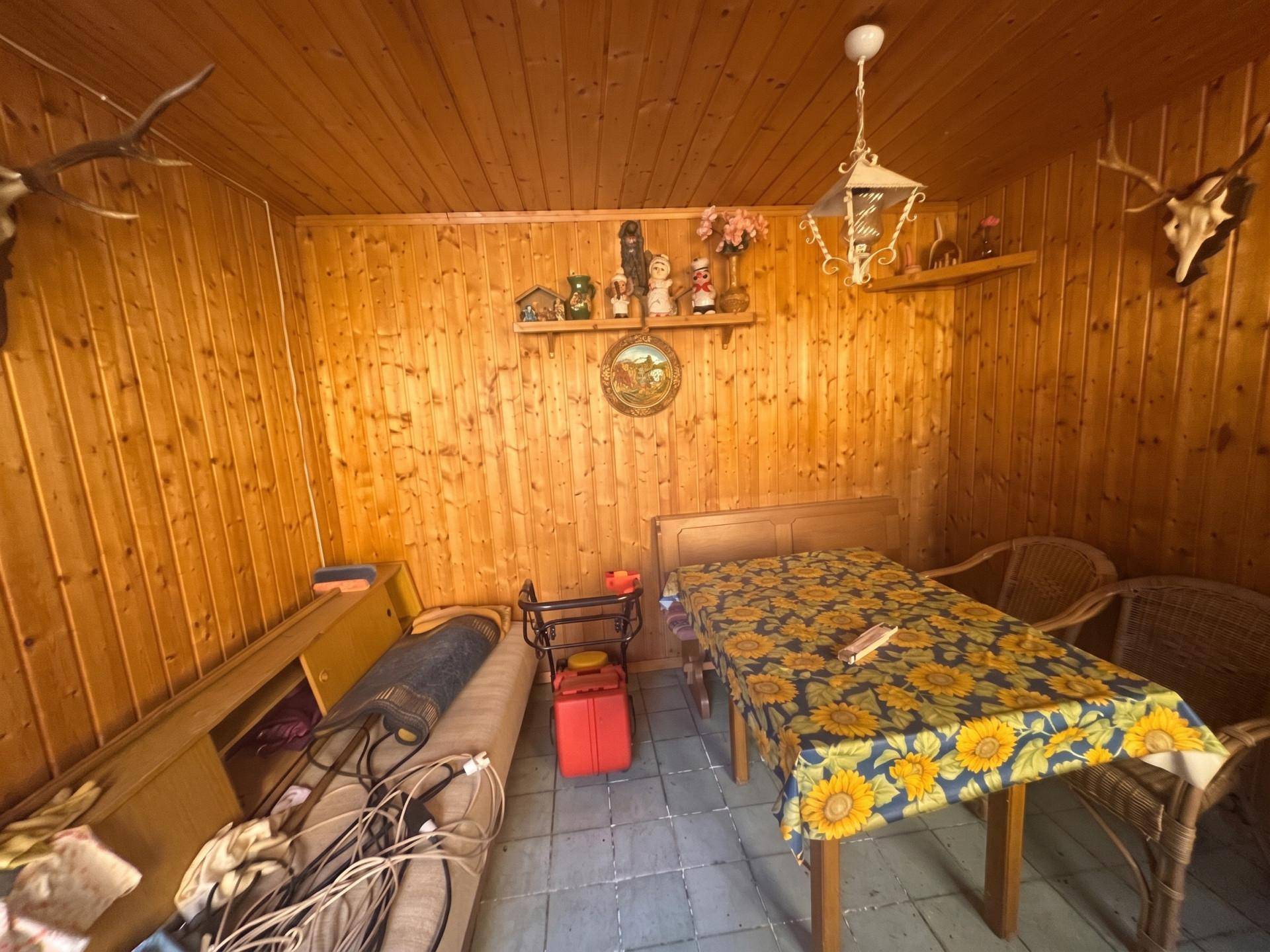 Rustikaler Raum mit Holzvertäfelung, gefliestem Boden und Jagdtrophäen an den Wänden.