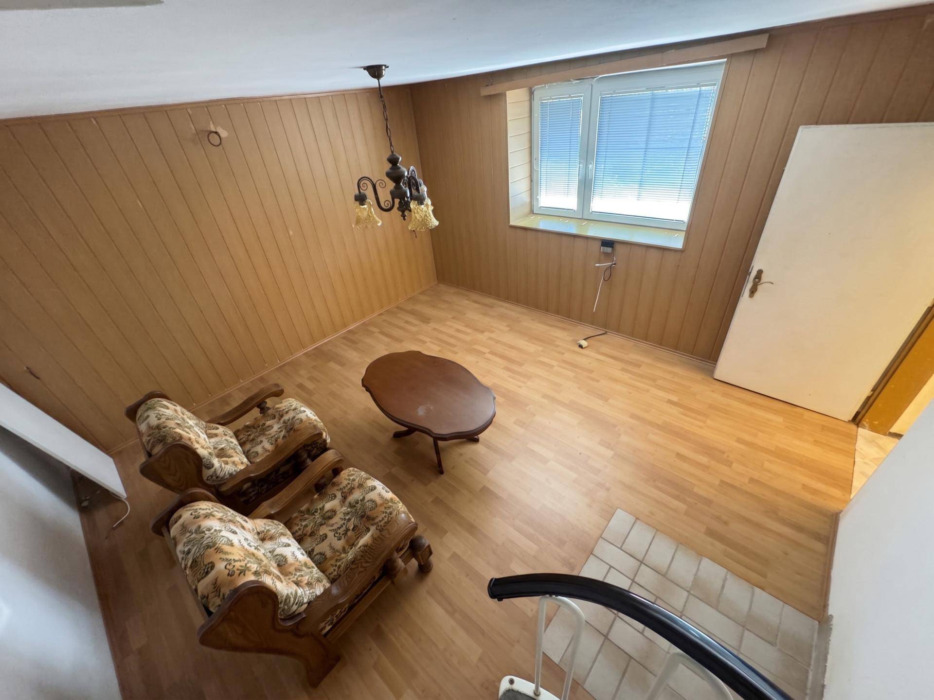 Wohnraum mit Holzvertäfelung, Holzboden und zwei klassischen Sesseln.