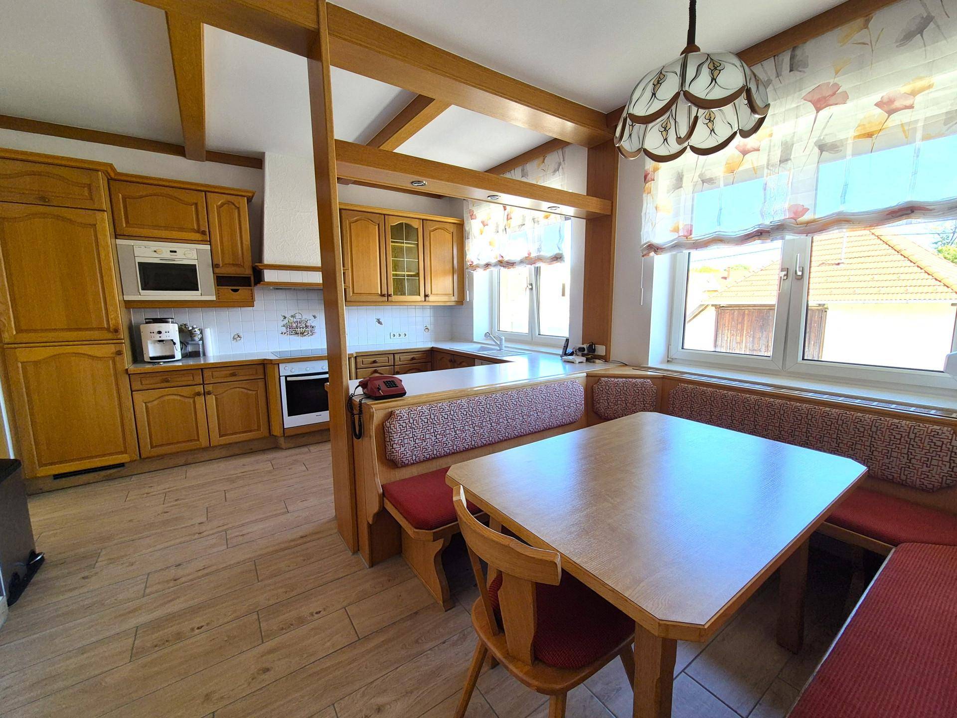Gemütliche Wohnküche im Landhausstil mit Holzelementen, Einbauküche und Essecke.