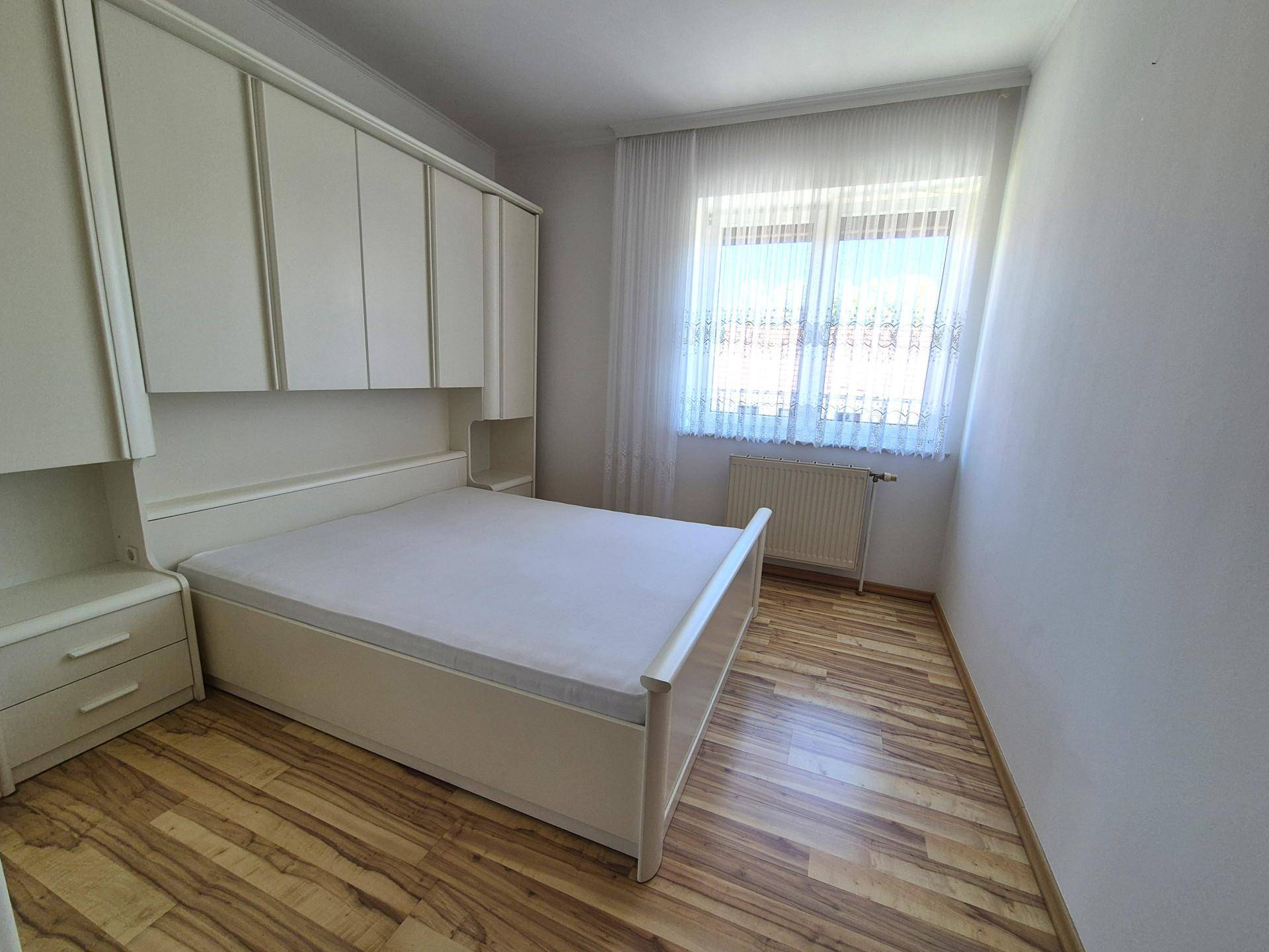 Schlafzimmer mit weißem Einbauschrank über dem Bett und hellem Laminatboden.