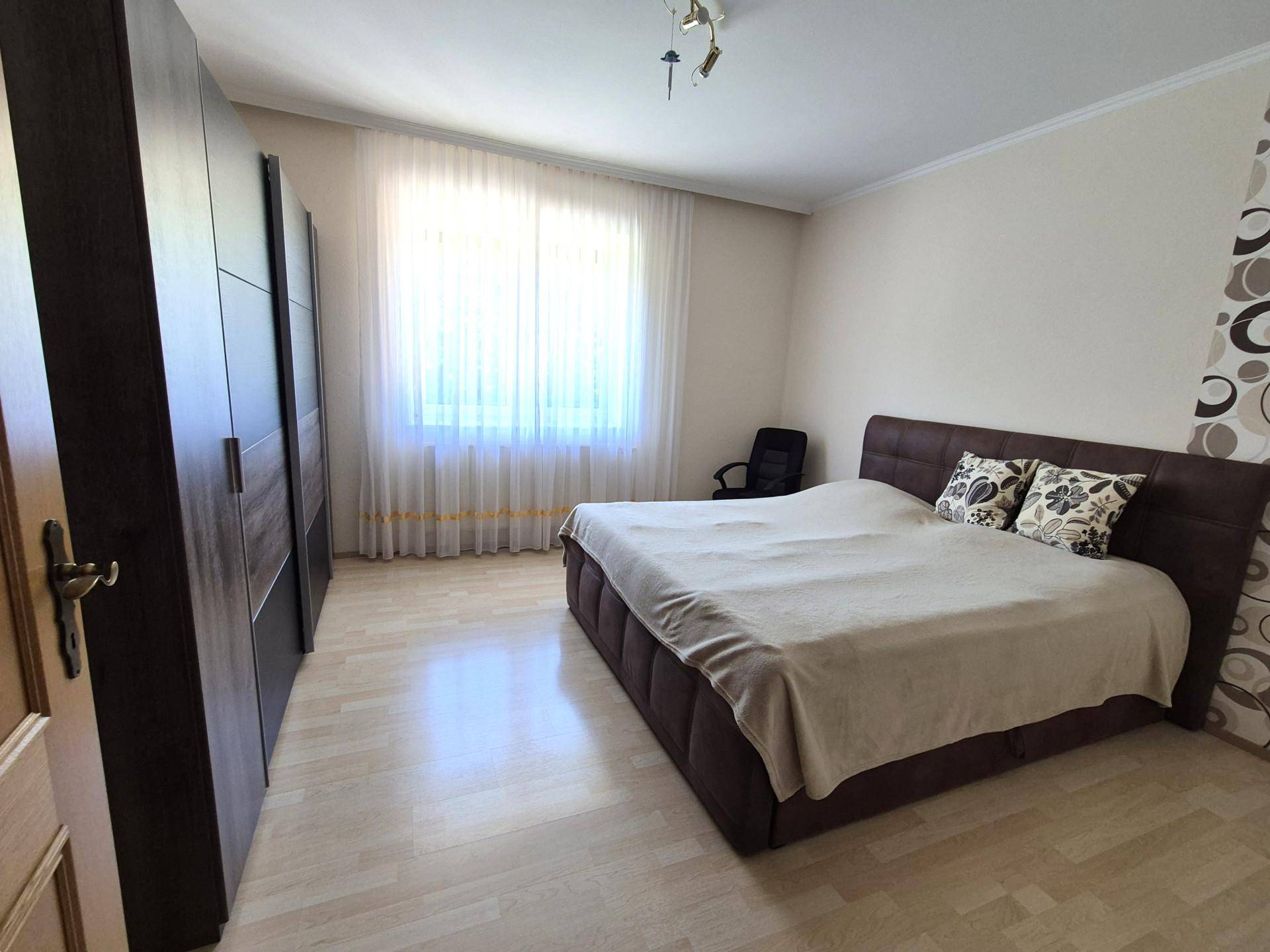 Helles Schlafzimmer mit Doppelbett, großem Kleiderschrank und Laminatboden.