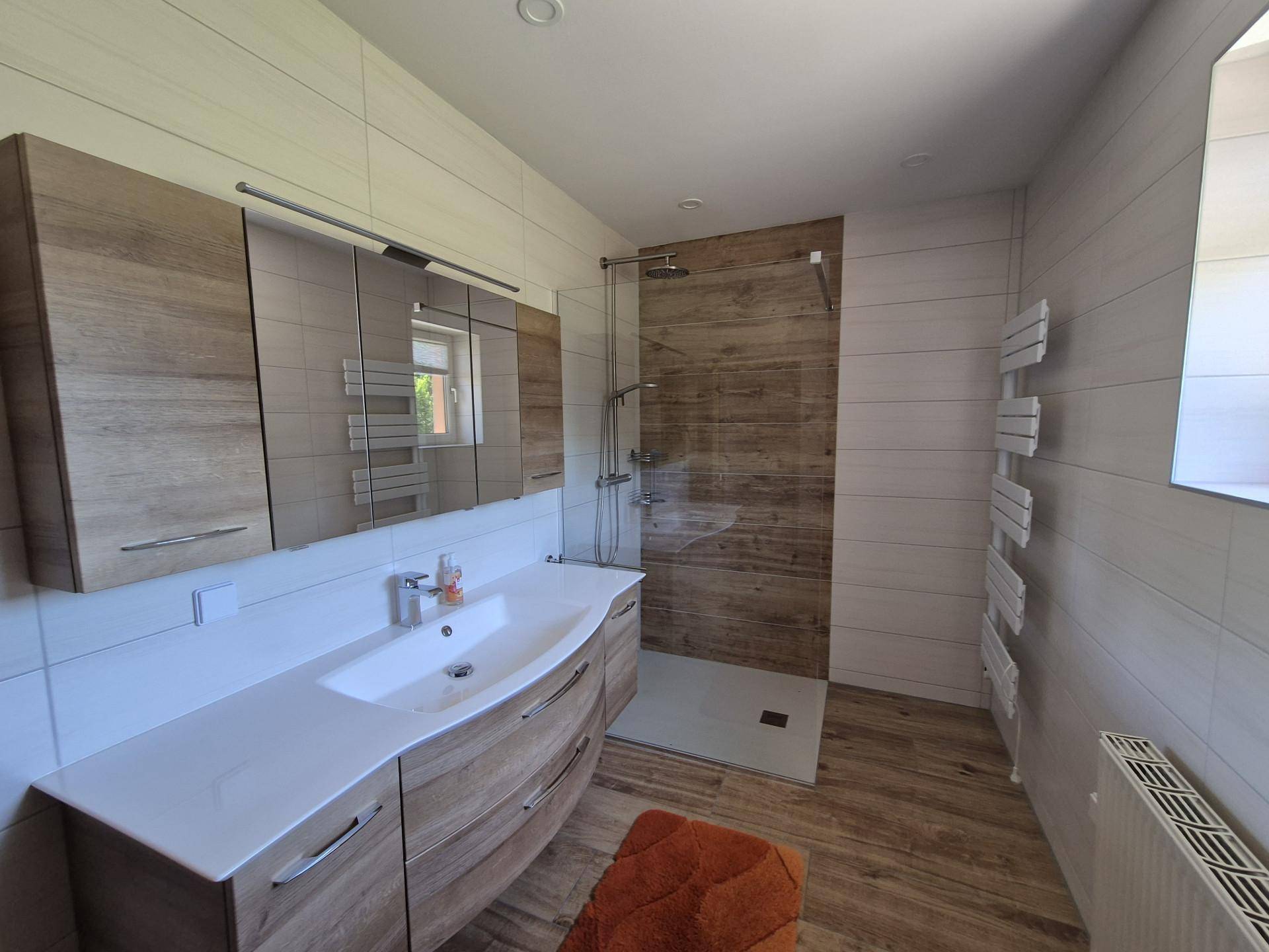 Modernes Badezimmer mit begehbarer Dusche, Holzoptikfliesen und Einzelwaschbecken.