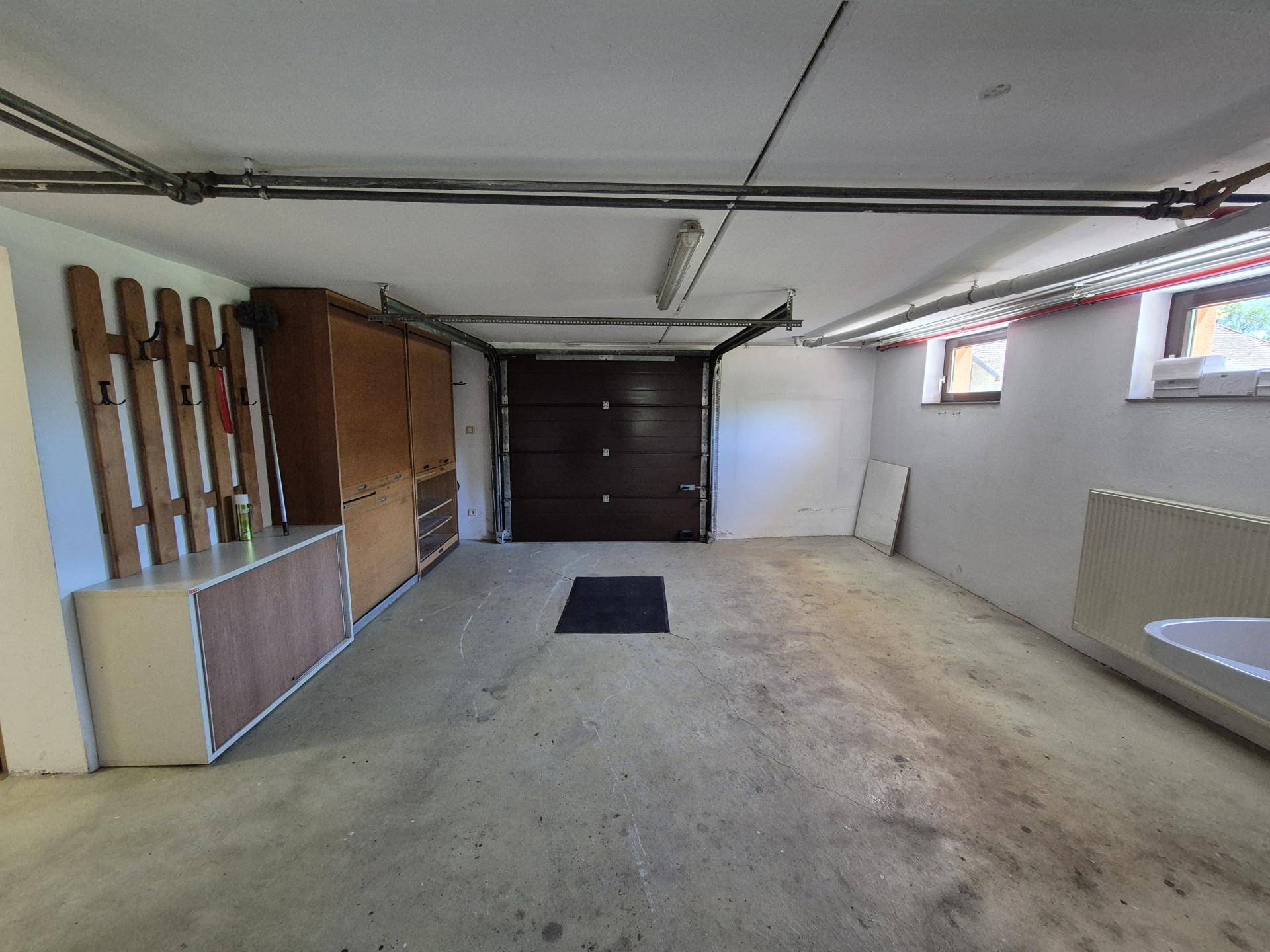 Geräumige Garage mit Betonboden, Rolltor und ausreichend Stauraum.