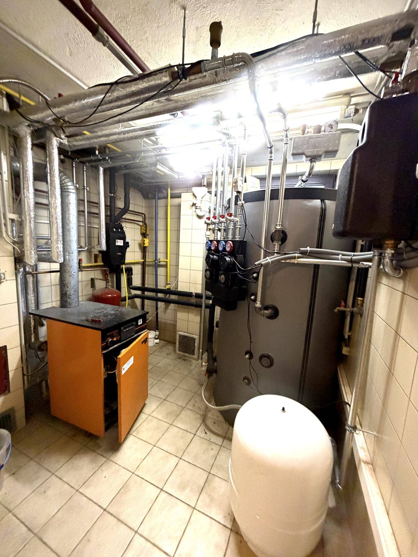 Heizungsraum mit modernen Heizkesseln, Warmwasserspeicher und sichtbaren Rohrleitungen.