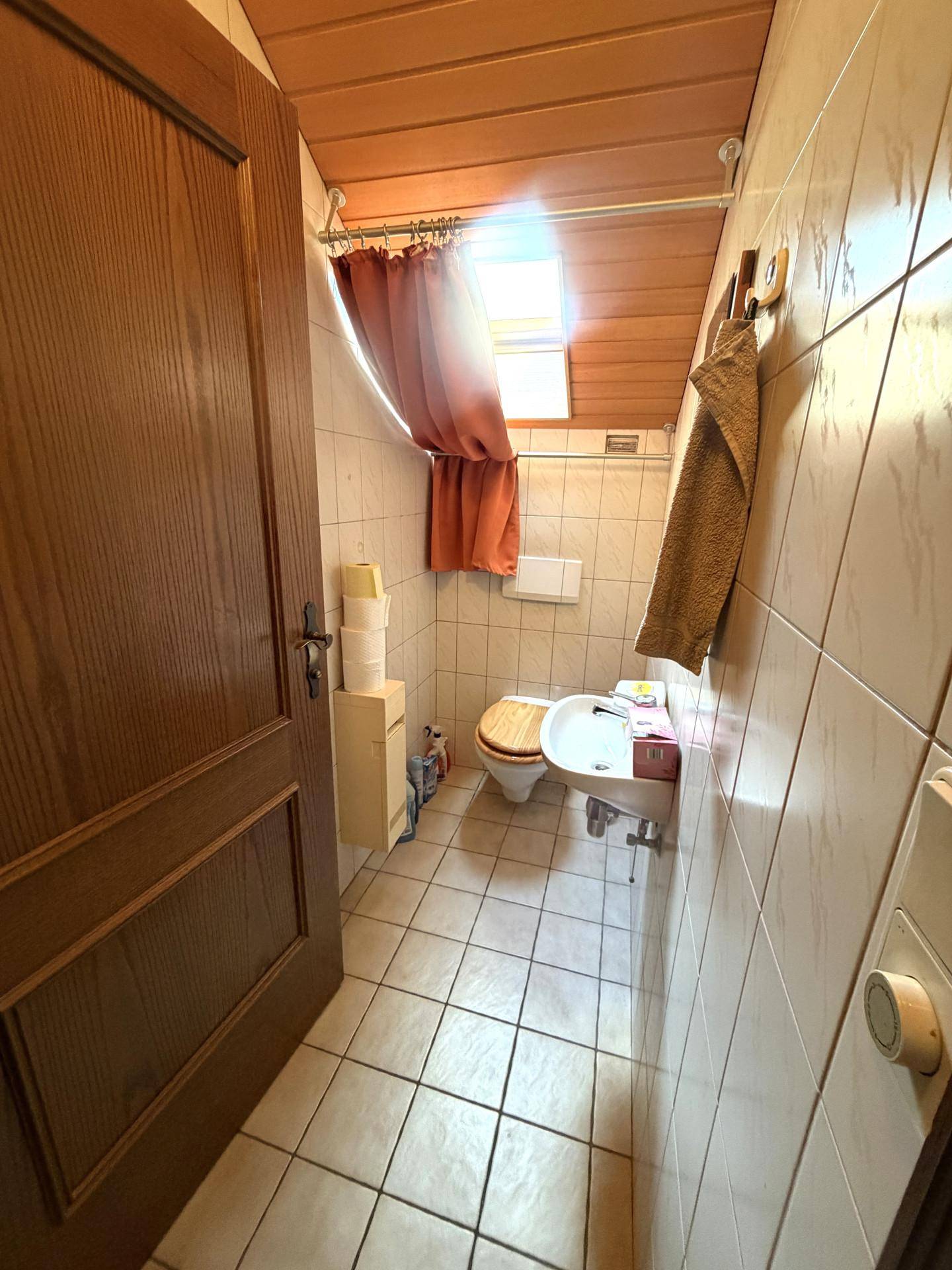 Kleines WC mit Bidet, Toilette und Fliesen an Wänden und Boden.