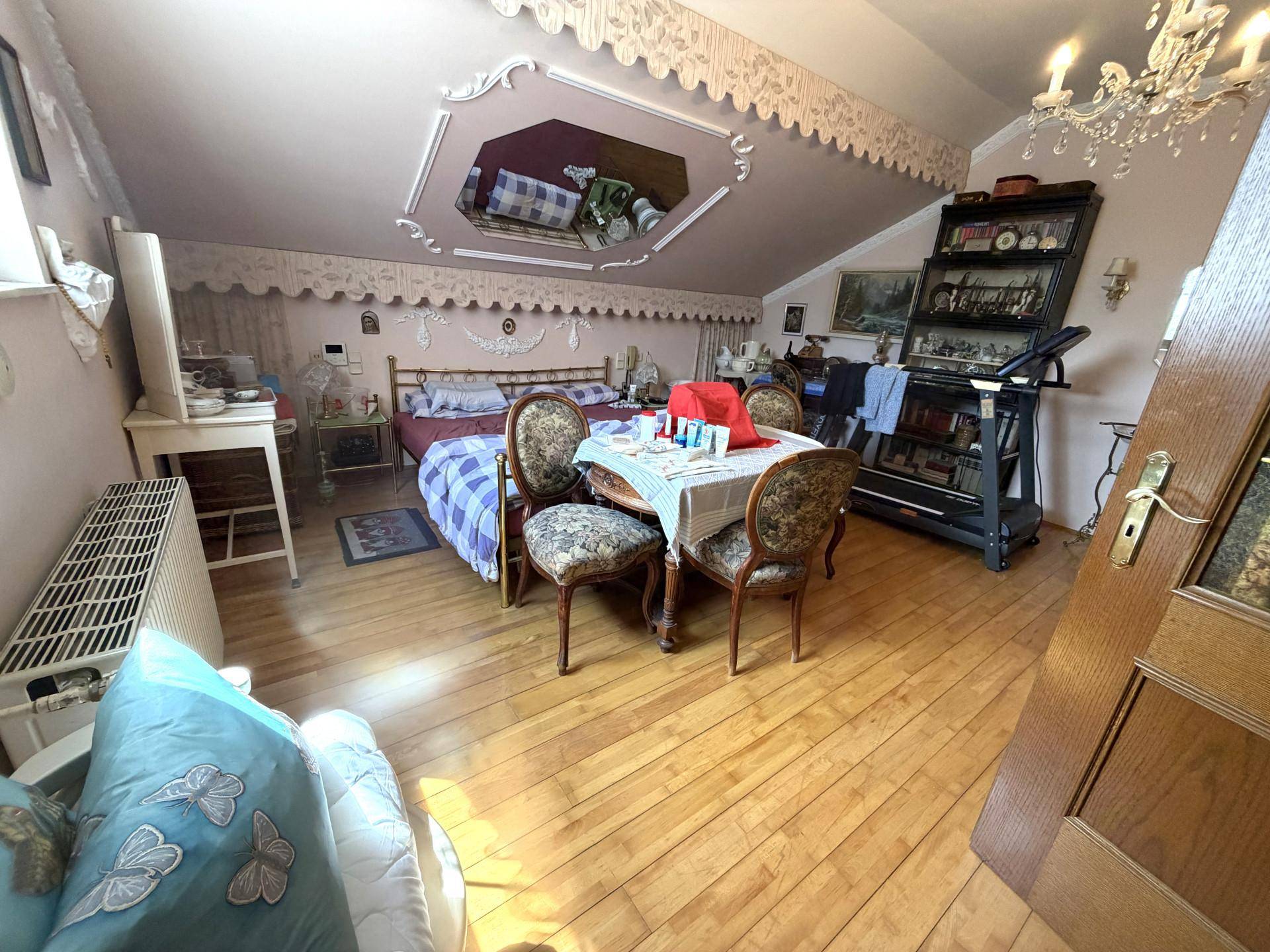 Schlafzimmer im Dachgeschoss mit Holzboden, Dachschräge und traditioneller Einrichtung.