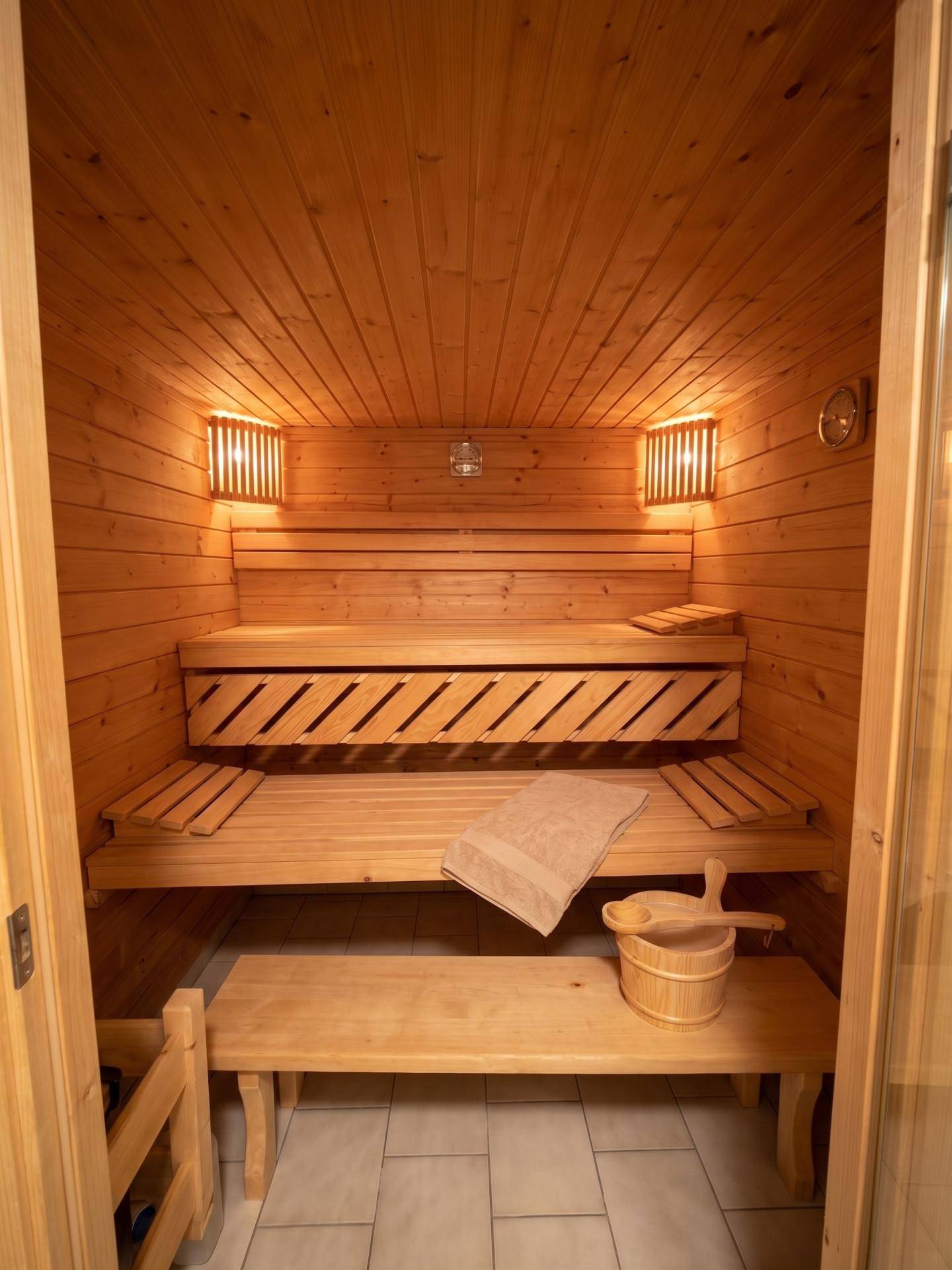 Gemütliche Holzsauna mit mehreren Bänken und stimmungsvoller Beleuchtung.