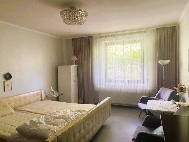 Geräumiges Schlafzimmer mit Doppelbett, großem Fenster und schlichten Möbeln.