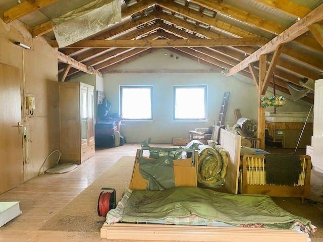 Geräumiger Dachboden mit sichtbaren Holzbalken und Fenstern, ideal für einen Ausbau.