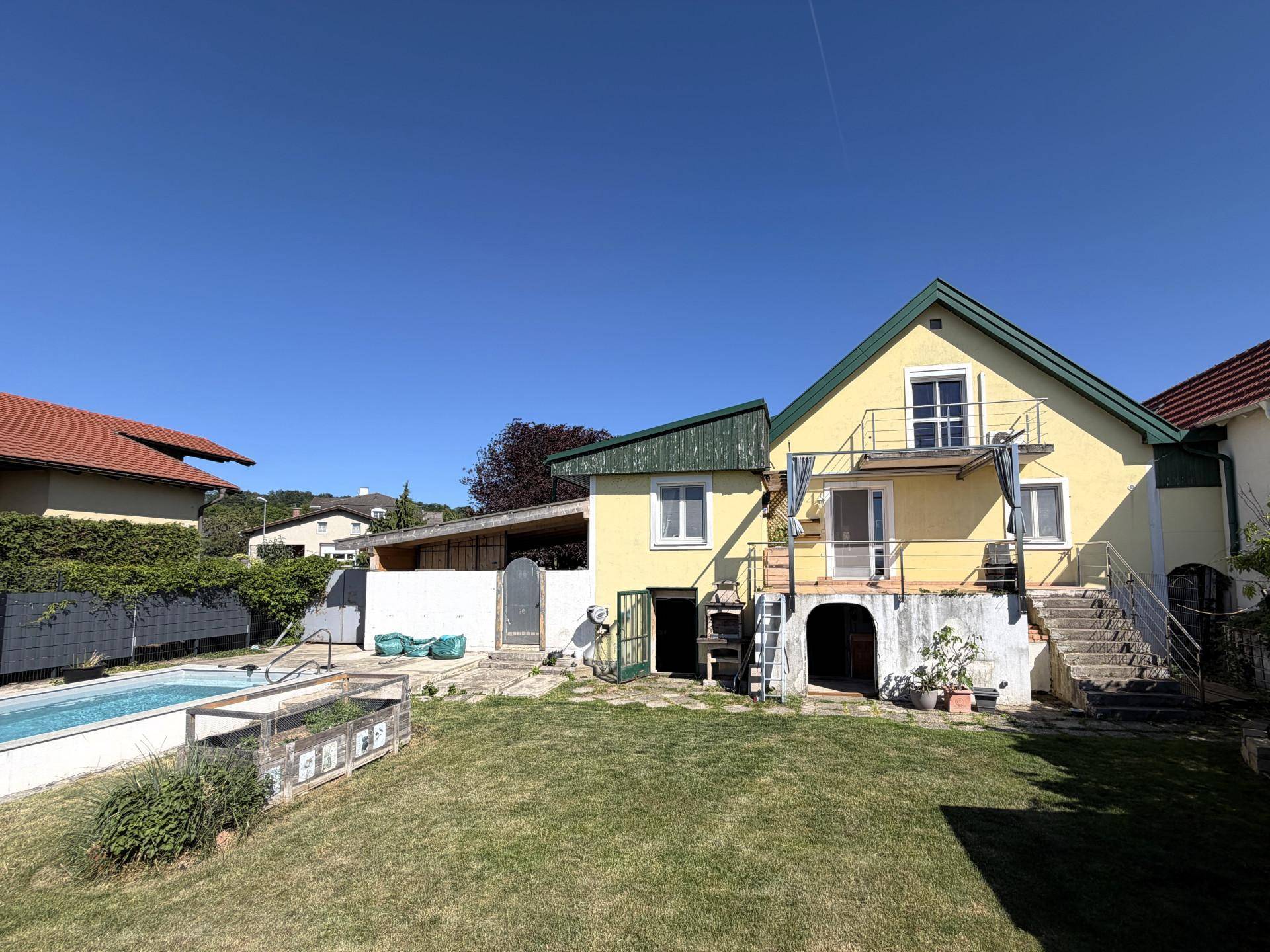 Hinteransicht des Hauses mit großem Garten, Rasenfläche und einem Swimmingpool.