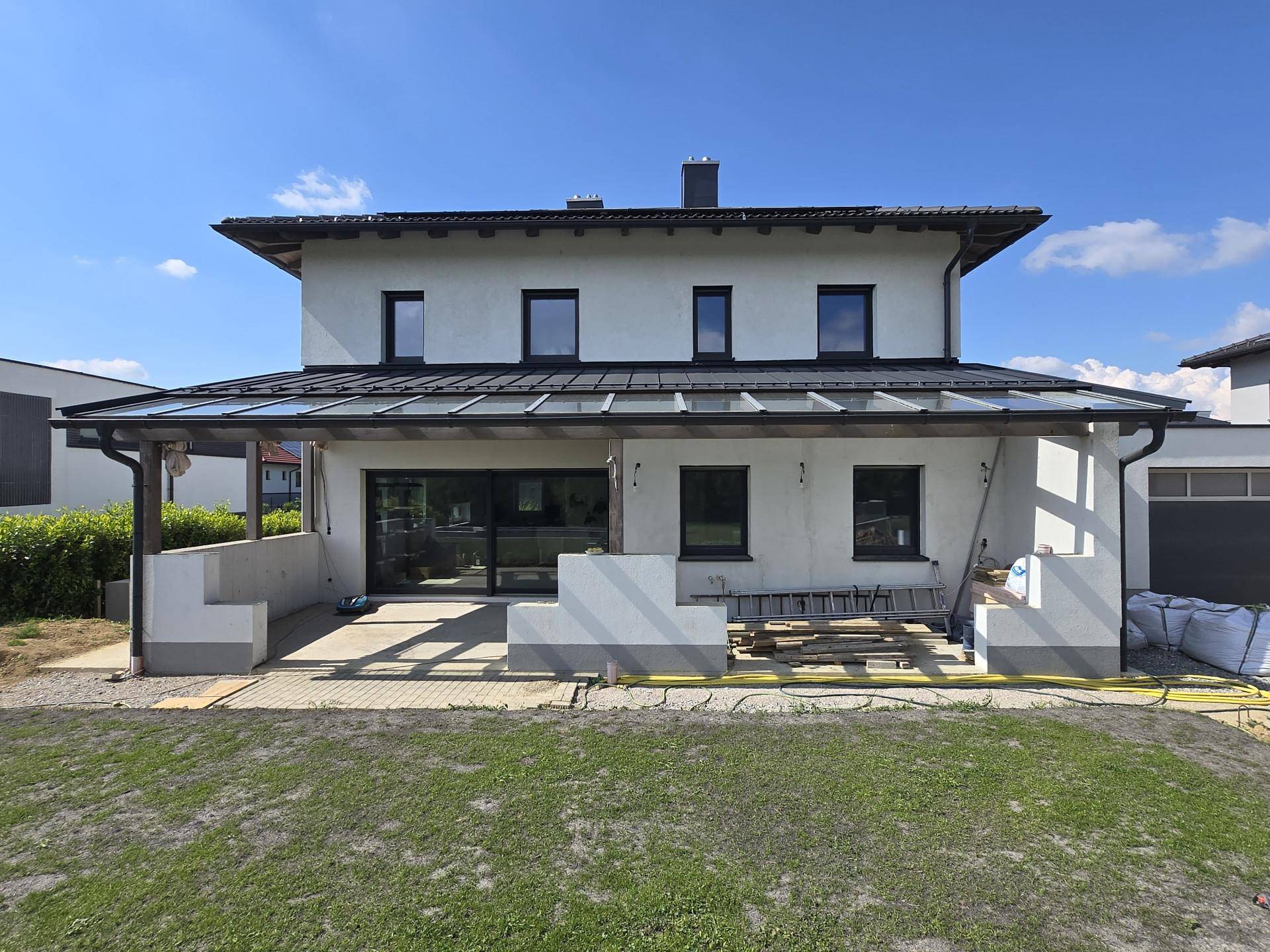 Rückseite des Hauses mit überdachter Terrasse im Bau und Blick auf den zukünftigen Gartenbereich.