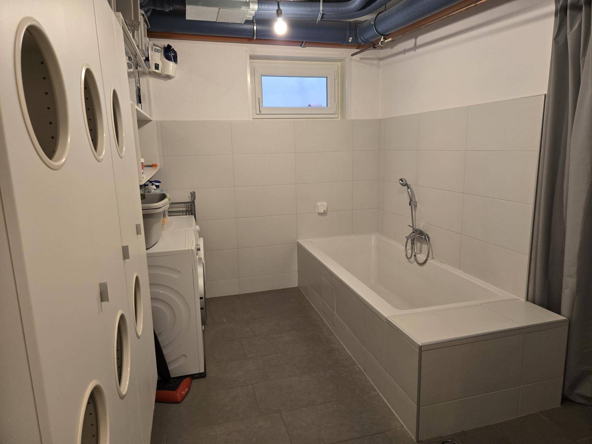 Praktischer Hauswirtschaftsraum mit Waschmaschine, Badewanne und Fliesenboden, ideal für Wäsche.