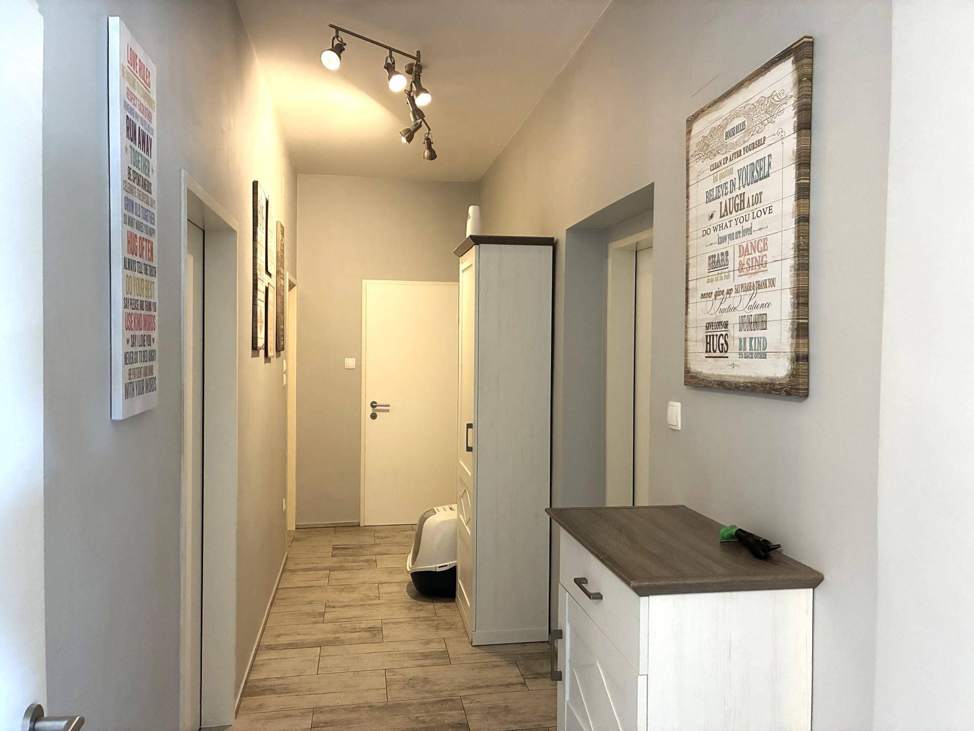 Heller Flur mit modernen Wandbildern, Schrank und Holzoptik-Fliesenboden.