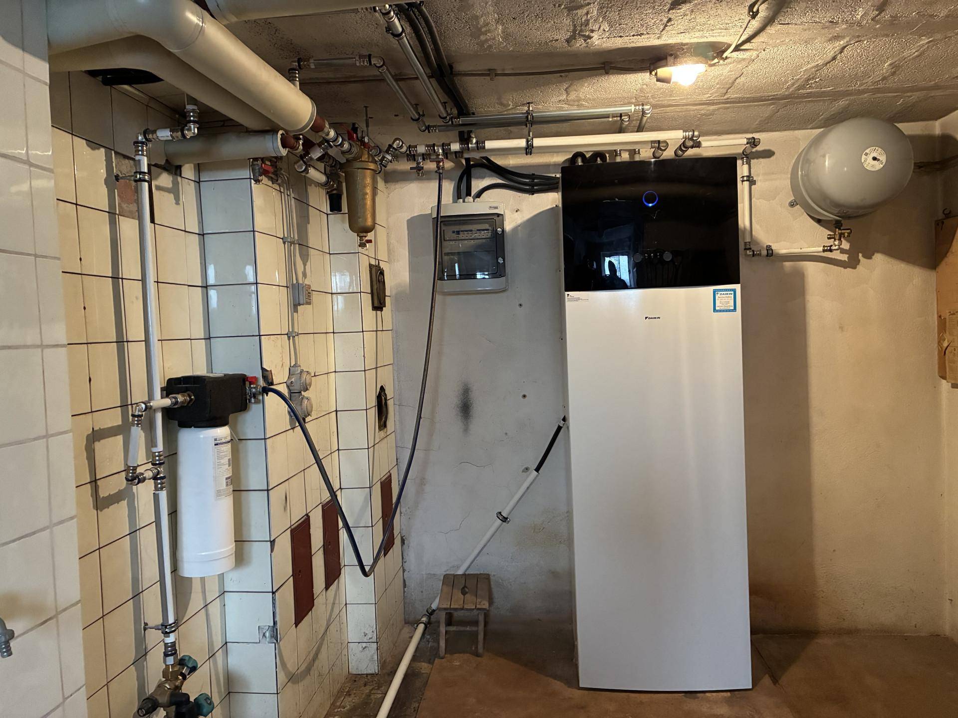 Heizungsraum im Keller mit moderner Wärmepumpe und Wasserleitungen.