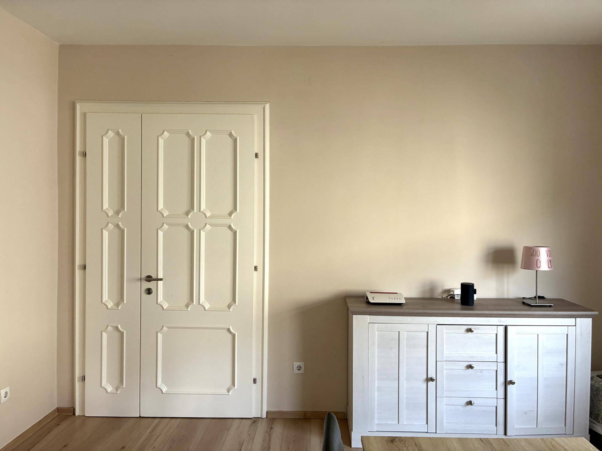 Wandbereich mit einer verzierten weißen Tür und einem Sideboard.