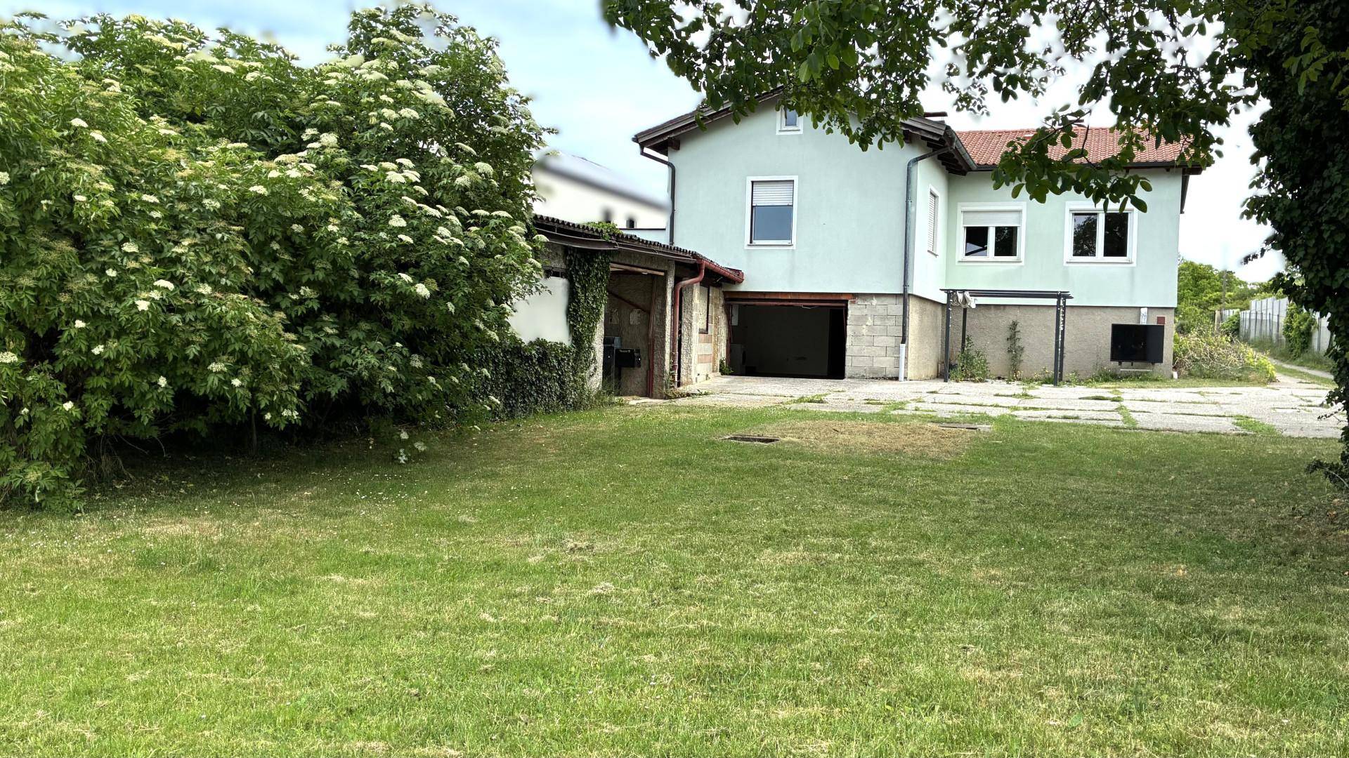 Rückansicht des Hauses mit großem Rasenbereich und angrenzender Garage.