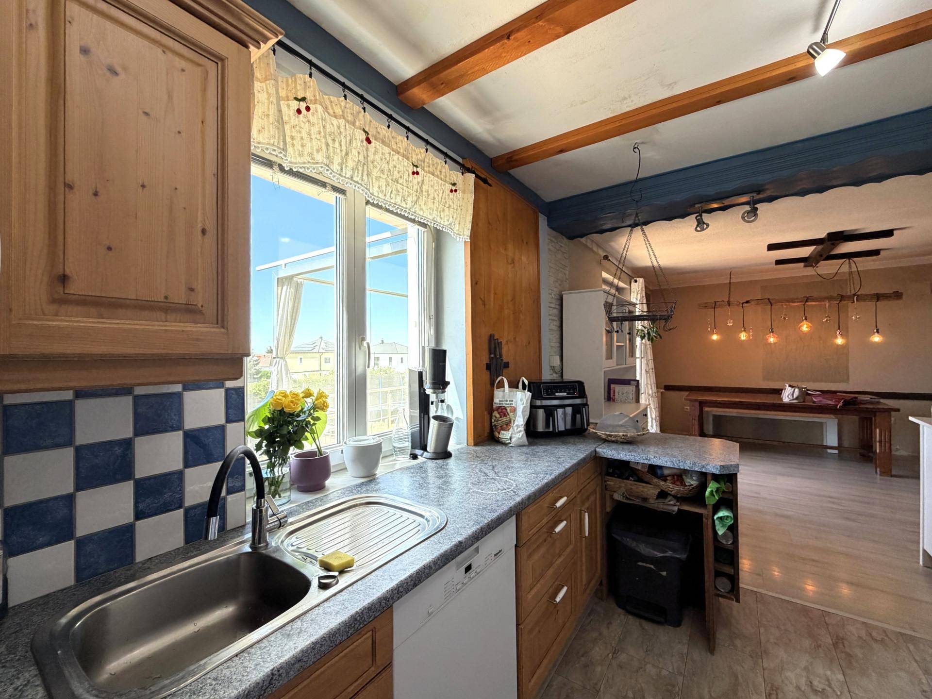 Rustikale Küche mit Holzschränken, blauen Fliesen und Blick ins Esszimmer.