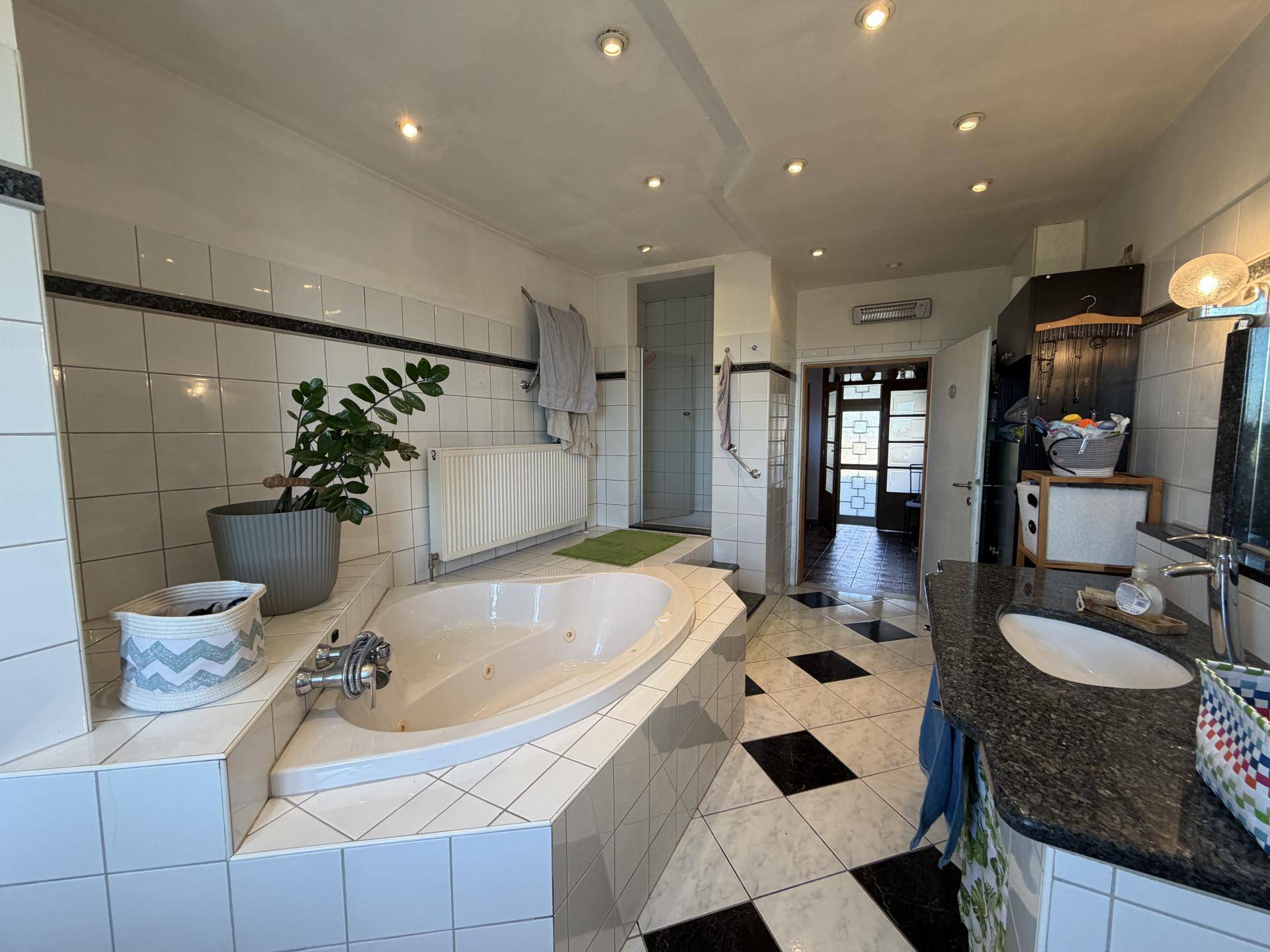Helles Badezimmer mit Eckbadewanne, Dusche und Granitwaschtisch.