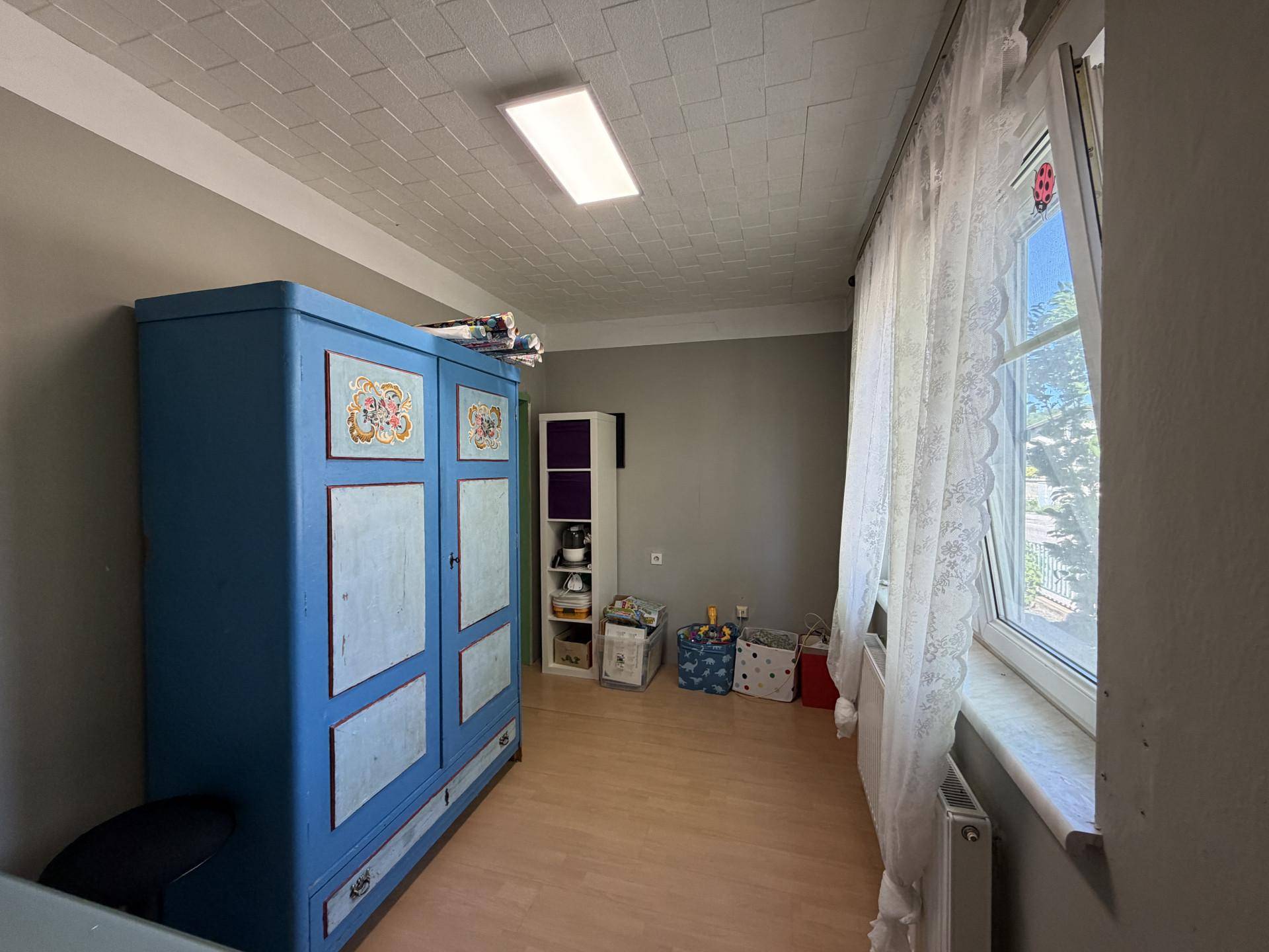 Helles Zimmer mit blauem Schrank, Holzfußboden und großem Fenster.