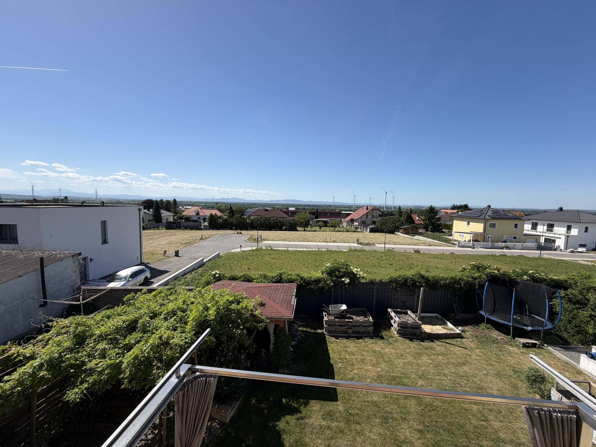 Panoramablick über die weite Landschaft mit Windrädern und umliegenden Häusern.