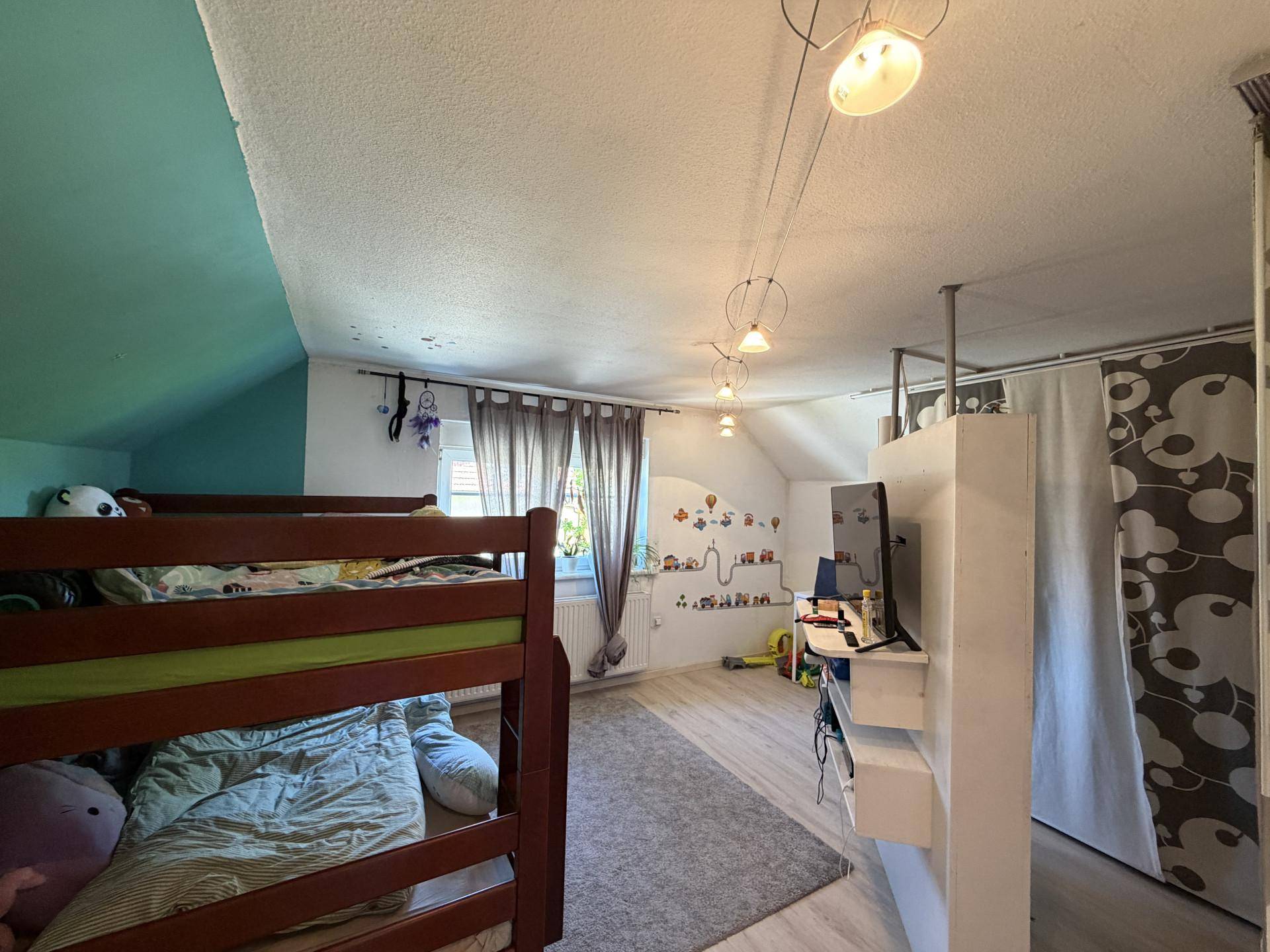Kinderzimmer mit Etagenbett, Dachschräge und spielerischer Wanddekoration.