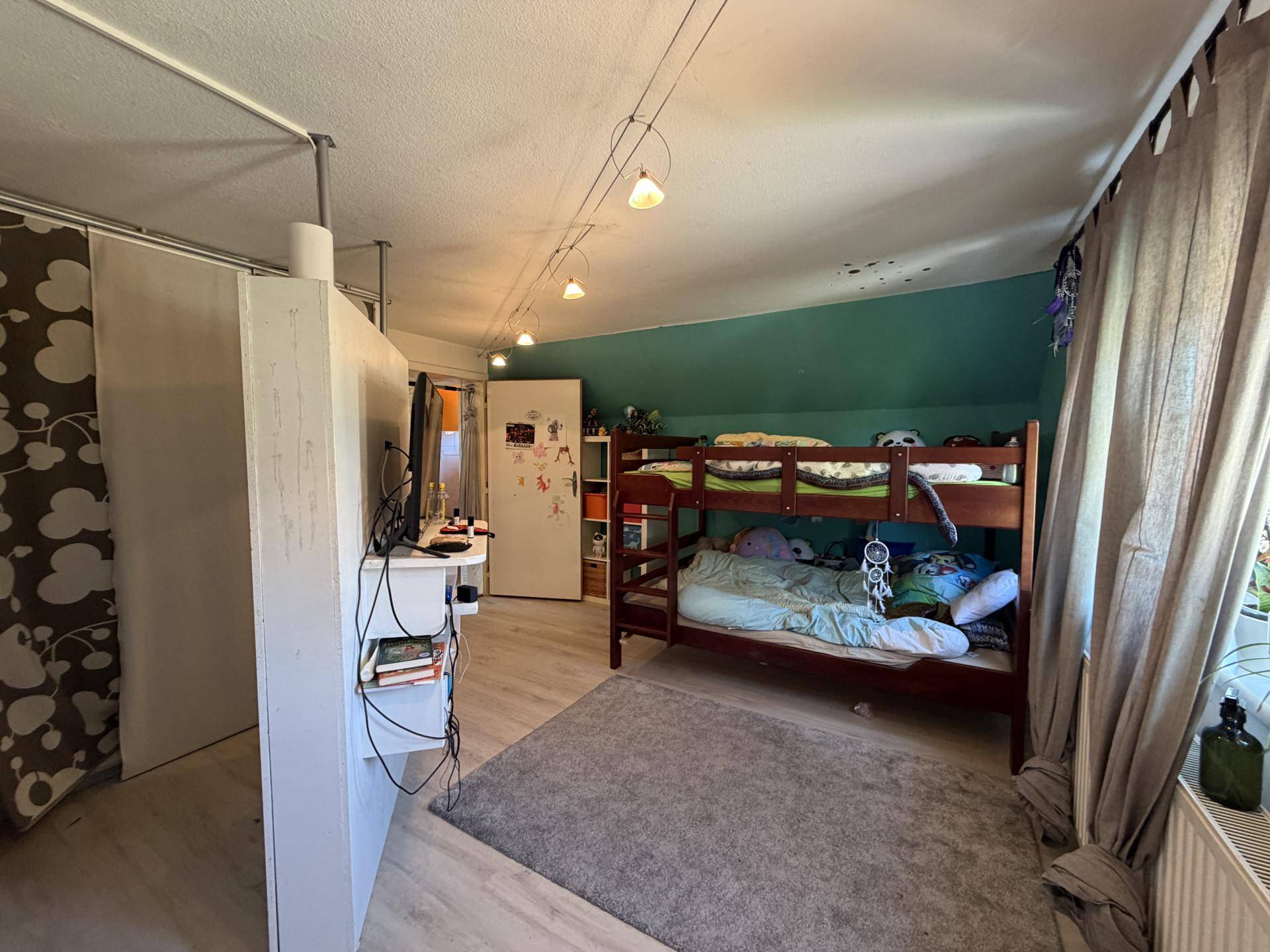 Geräumiges Kinderzimmer mit Etagenbett, Teppich und Blick auf den Garten.