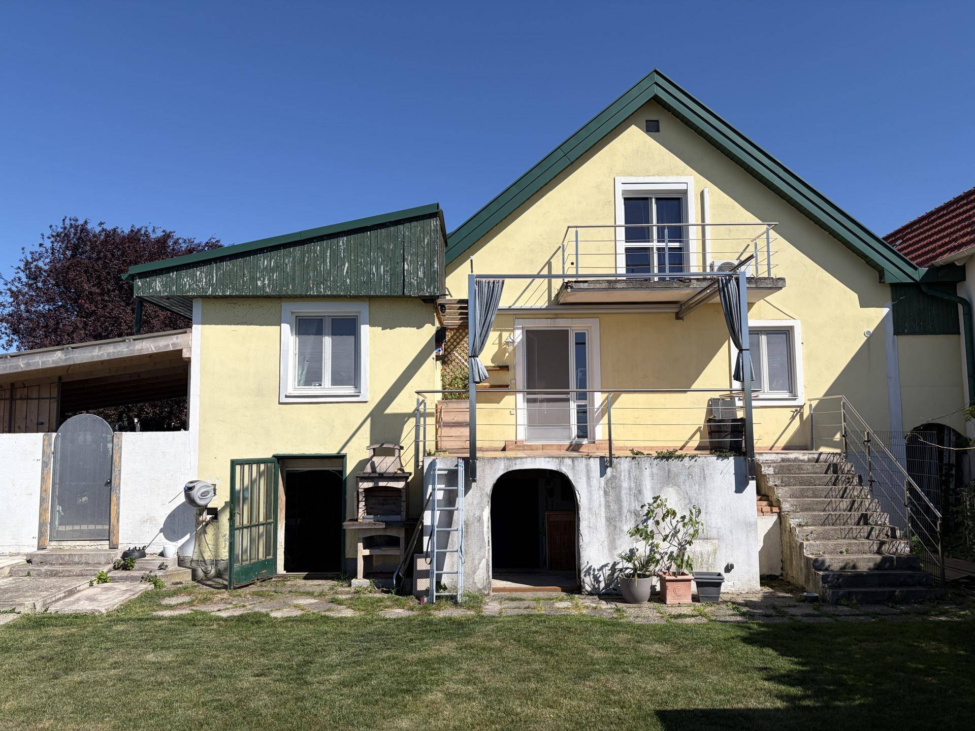 Rückseite des Hauses mit Garten, Rasenfläche und einem einladenden Swimmingpool.