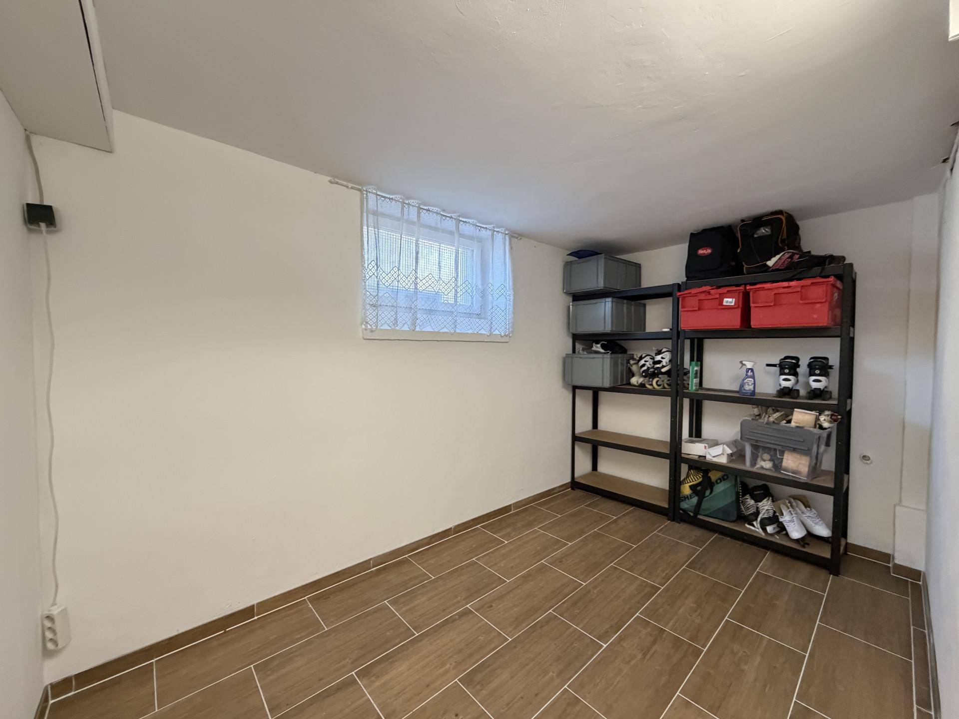 Kellerraum mit Fliesenboden, Regalen und einem kleinen Fenster.