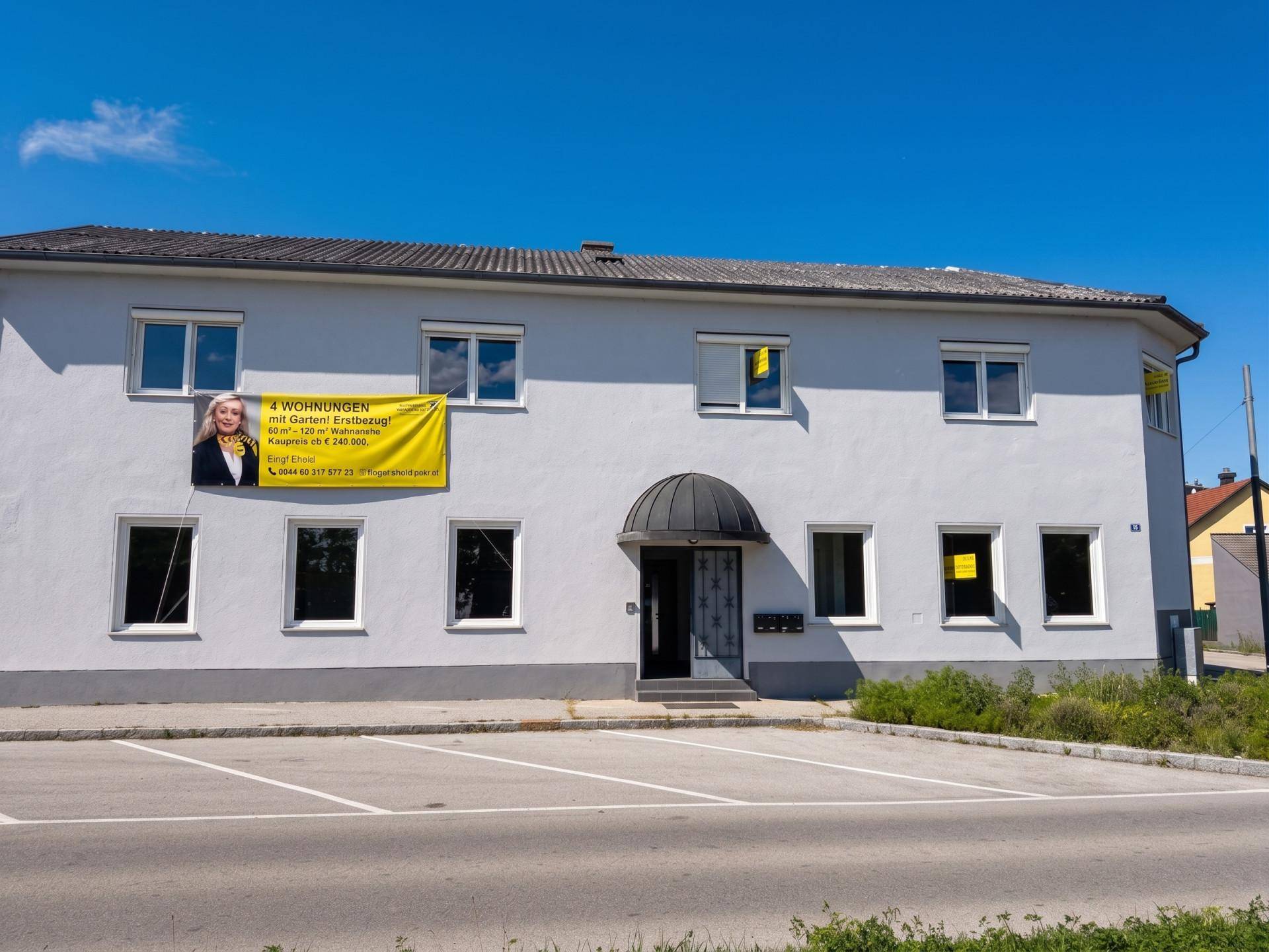 Fassade eines Wohngebäudes mit Werbebanner für verfügbare Wohnungen und Parkplätzen.