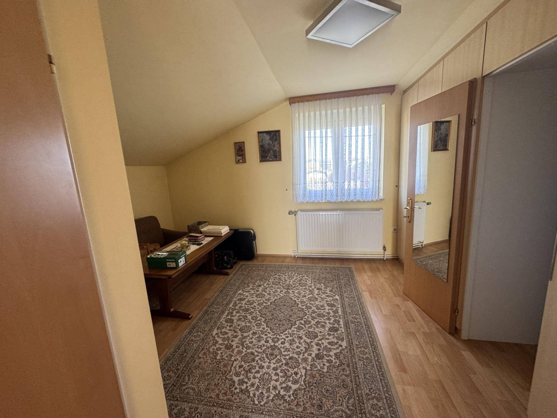 Helles Schlafzimmer im Dachgeschoss mit Dachschräge, Teppich und Fenster.