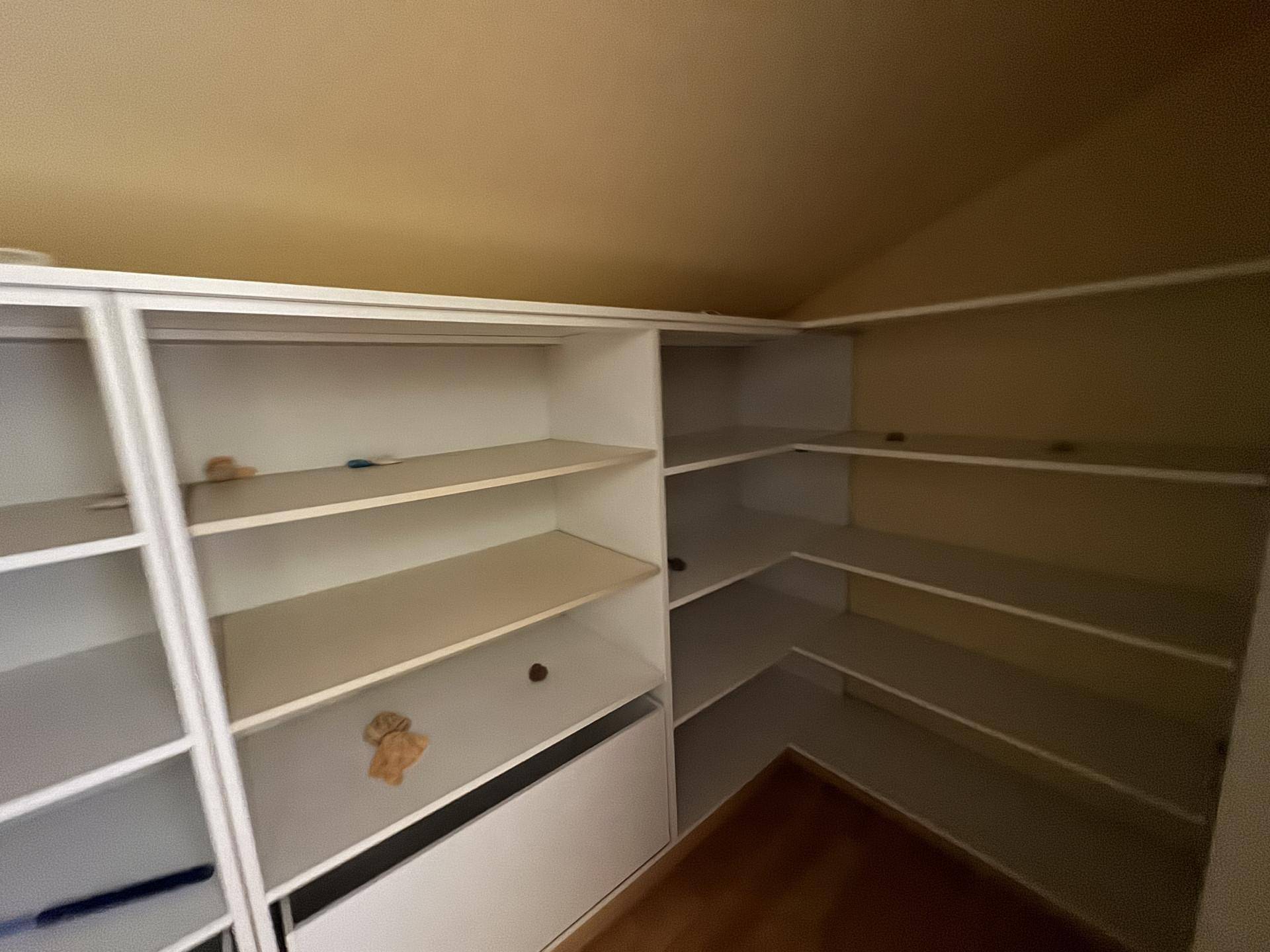 Praktischer Abstellraum mit vielen Regalen und Dachschräge für zusätzlichen Stauraum.