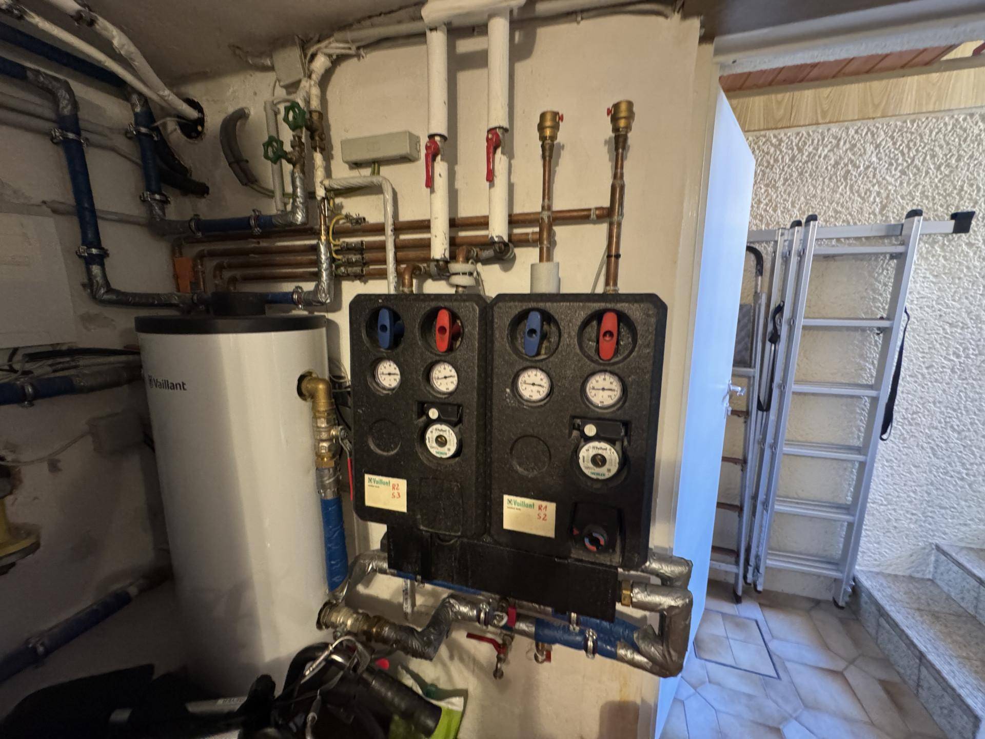 Heizungsraum im Keller mit moderner Heizungsanlage und Warmwasserspeicher.