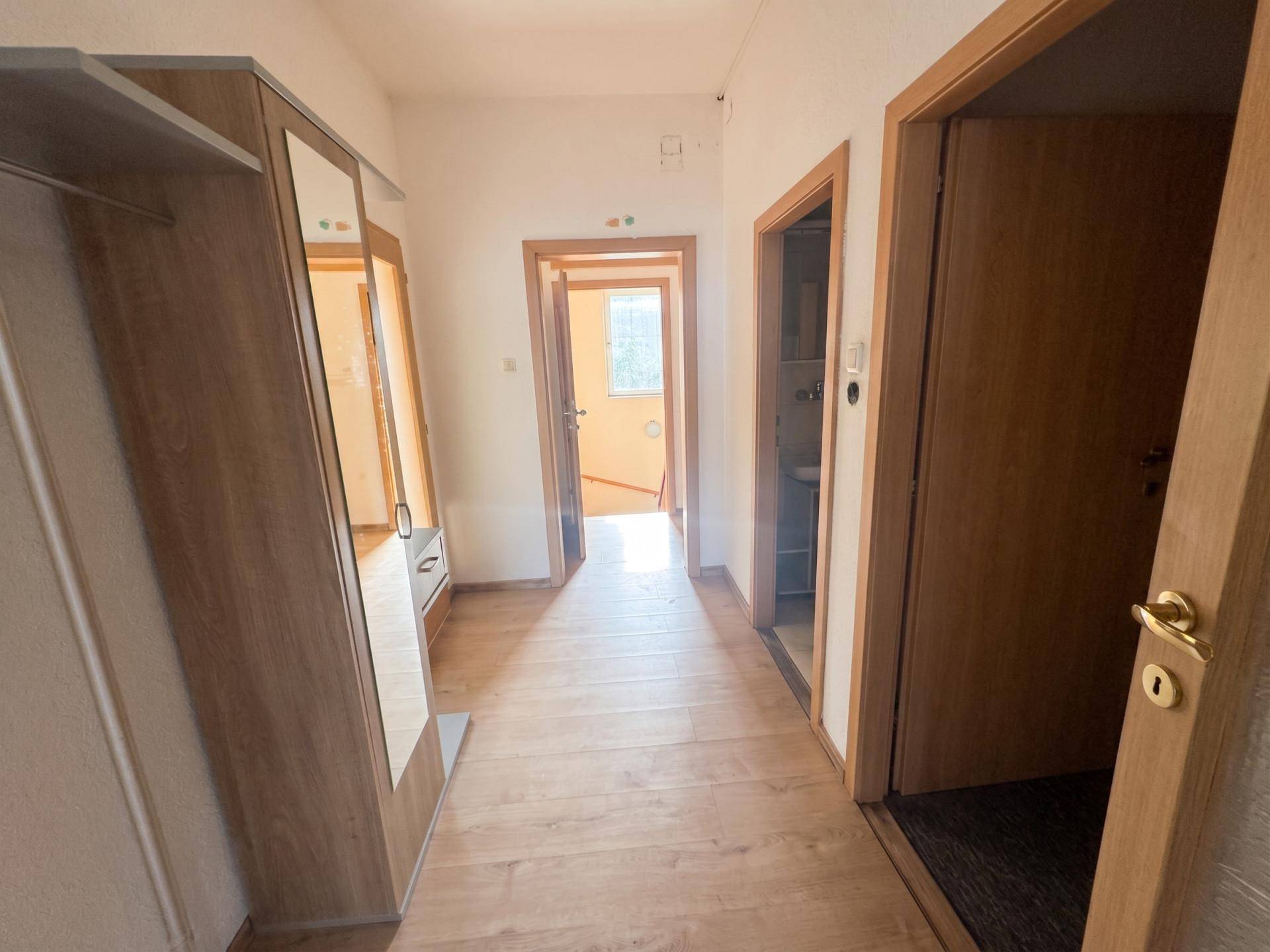 Flur mit Laminatboden, Spiegelschrank und mehreren Türen, die zu den angrenzenden Räumen führen.