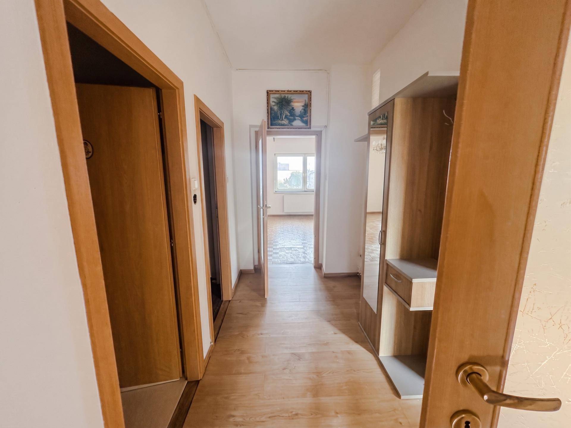 Heller Flur mit Laminatboden, Spiegelschrank und Türen, die zu den verschiedenen Räumen führen.
