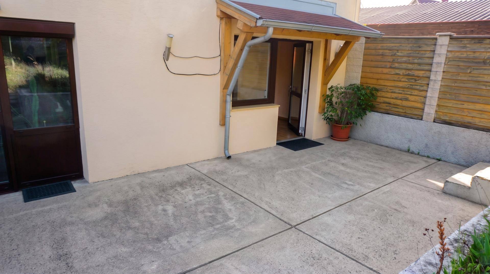 Betonierte Terrasse am Hauseingang mit Überdachung und Topfpflanze, ideal für den Empfang.
