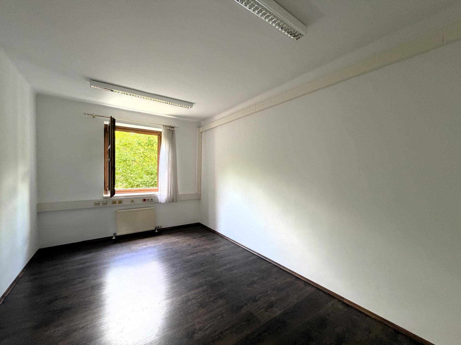Leerer Raum mit einem Fenster, dunklem Boden und weißen Wänden, bietet vielseitige Nutzungsmöglichkeiten.