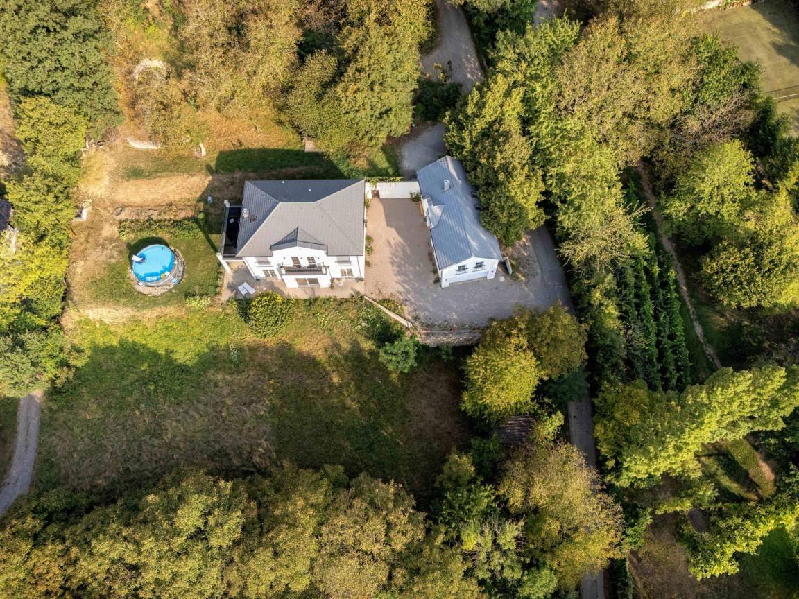 Luftaufnahme des Anwesens mit Haupthaus, Nebengebäude und umgebender Natur.