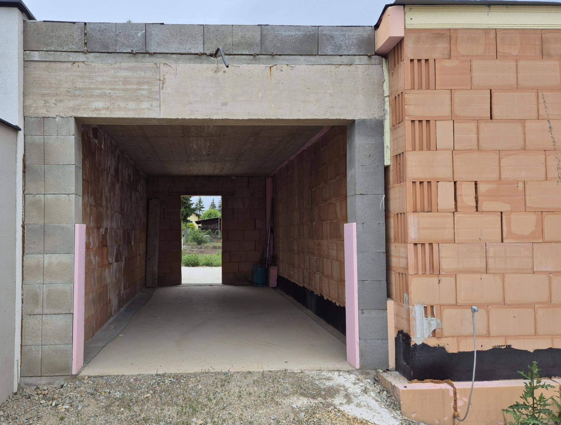 Eingangsbereich zu einem Garagen- oder Abstellraum im Rohbau mit Ziegelwänden und Betonsturz.