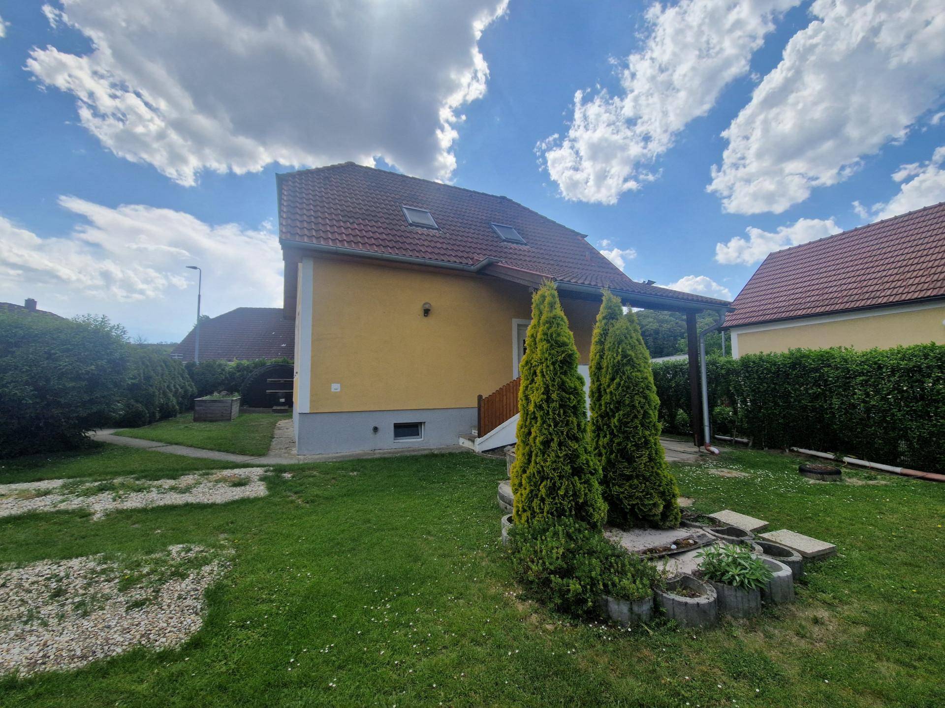 Seitenansicht des Hauses mit überdachtem Eingangsbereich und gepflegtem Garten.