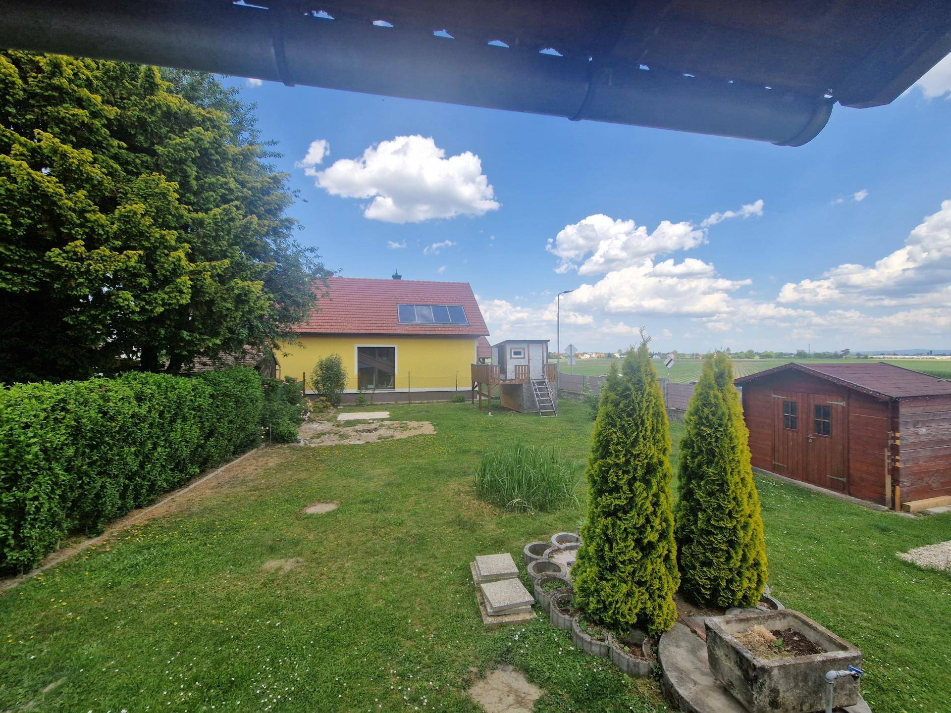 Weitläufiger Blick über den grünen Garten und die umliegende Landschaft unter blauem Himmel.