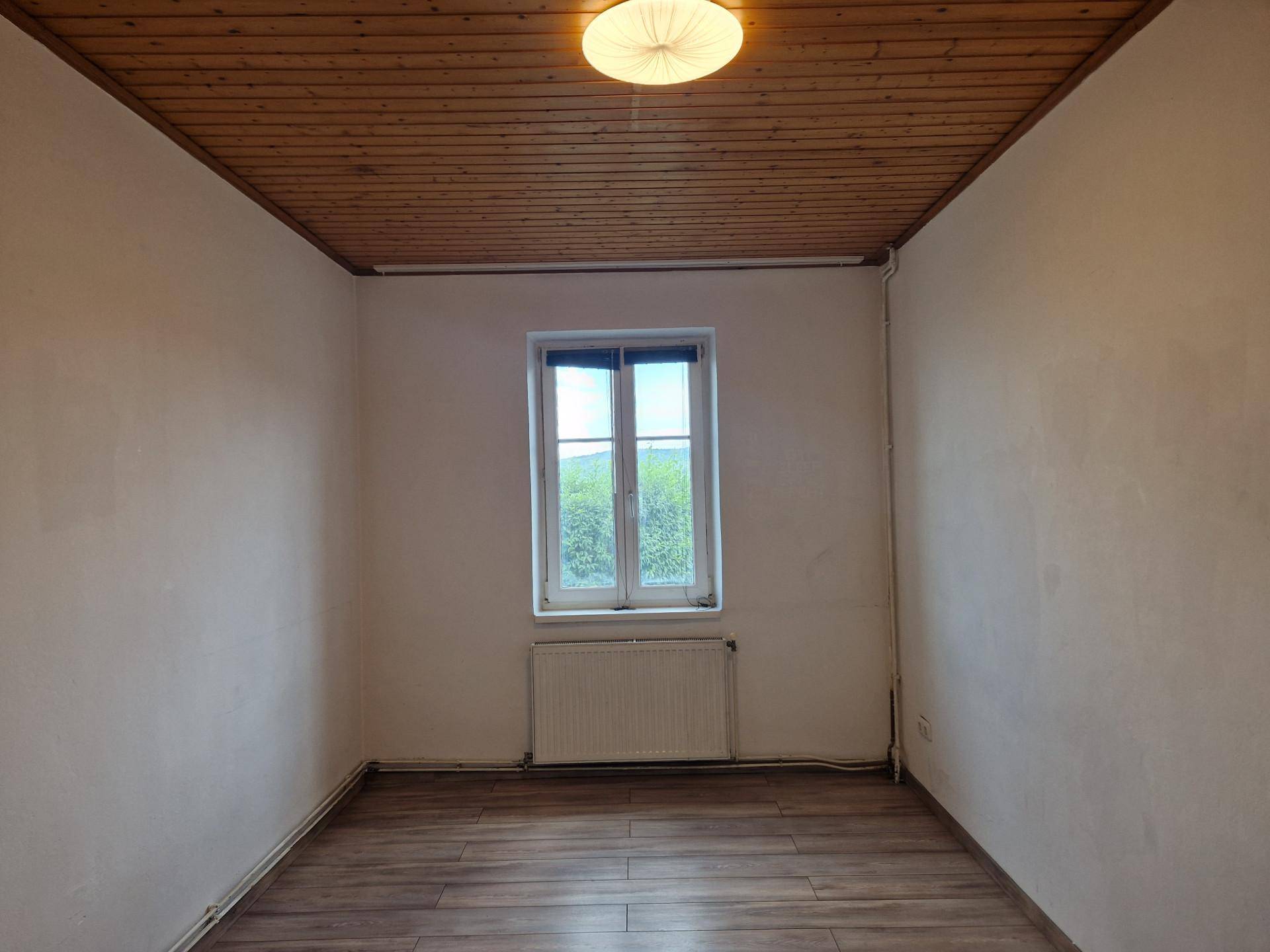 Heller Raum mit Holzdielen-Decke, Laminatboden und Fenster mit Ausblick.