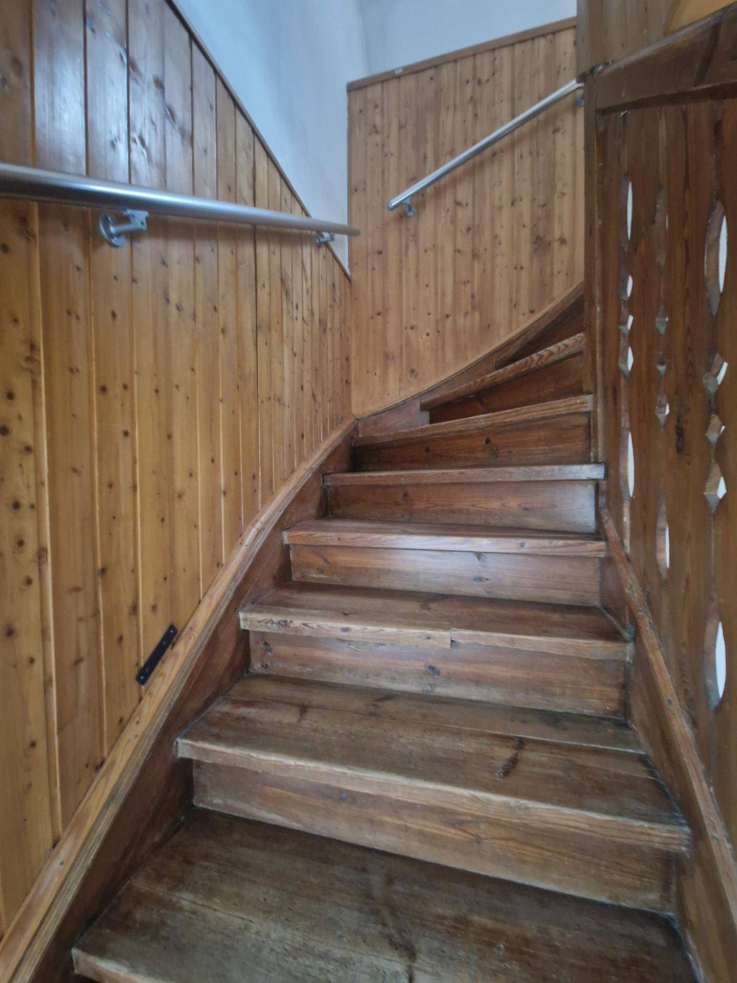 Rustikale Holztreppe mit Metallgeländer, die in die obere Etage führt.