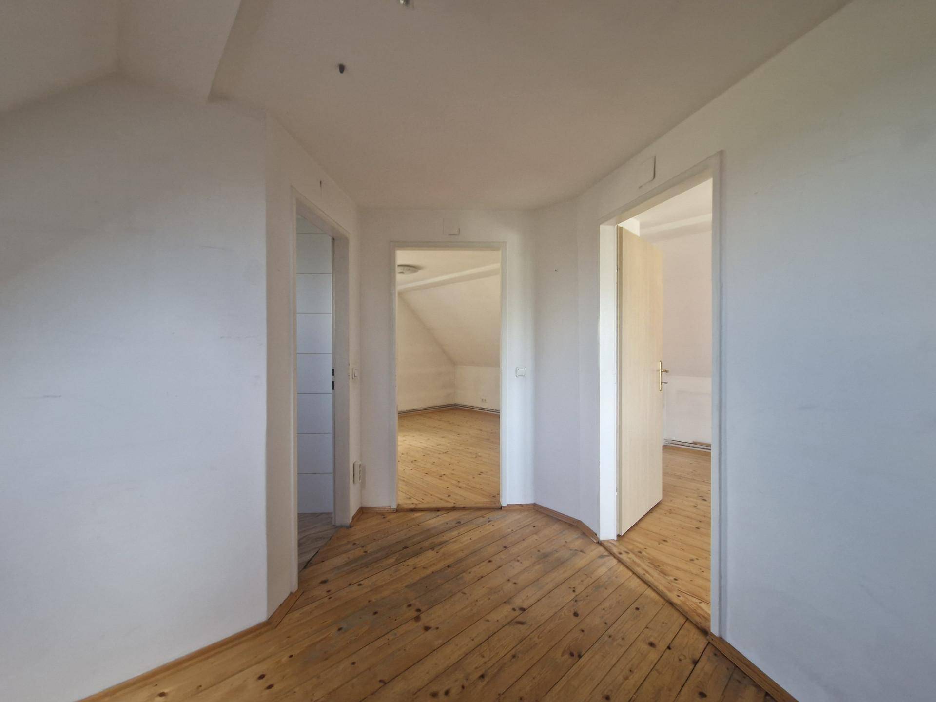 Heller Flur im Obergeschoss mit Holzdielenboden und Zugang zu mehreren Zimmern.