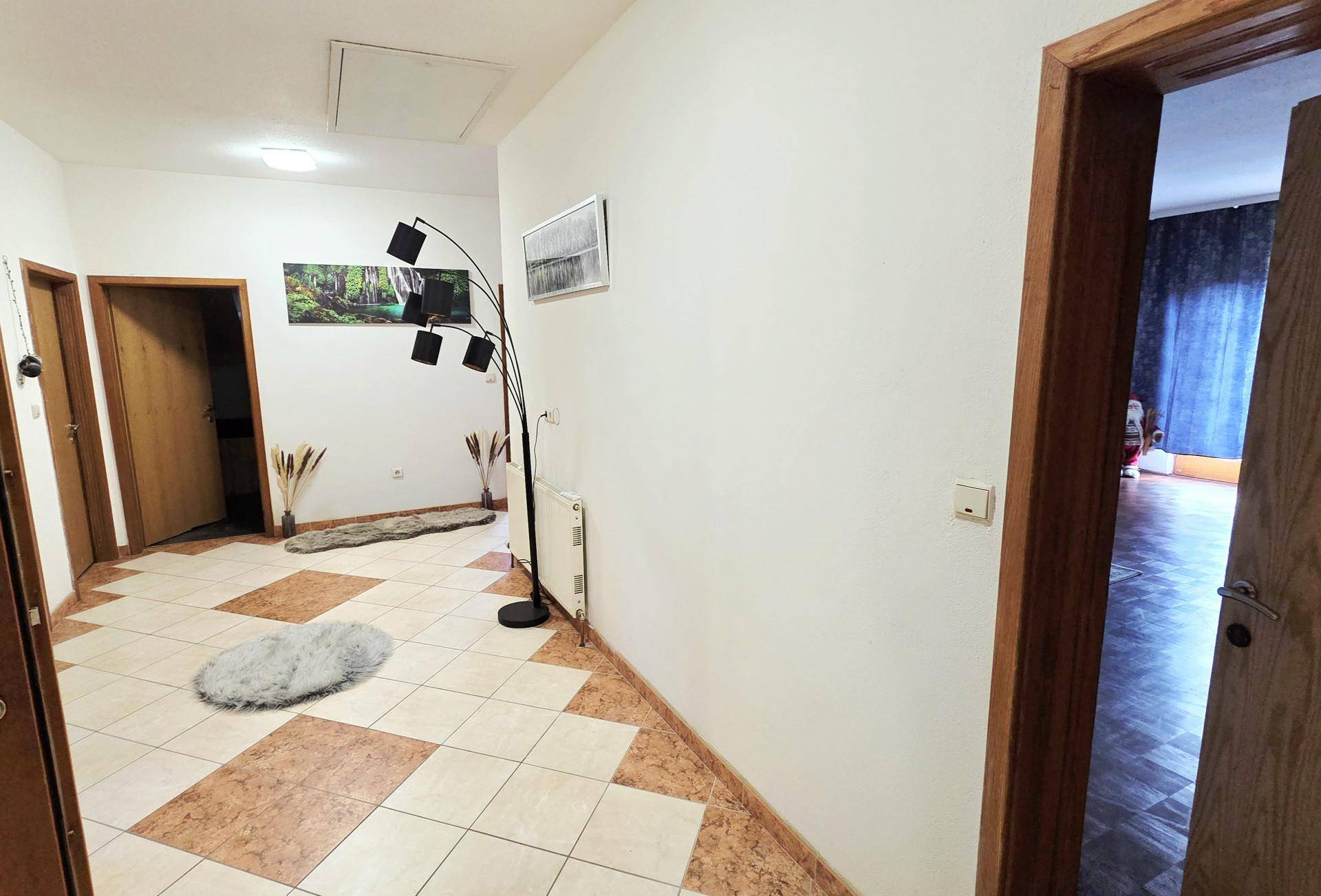 Flur mit gemustertem Fliesenboden, Stehlampe und mehreren Türen zu angrenzenden Räumen.