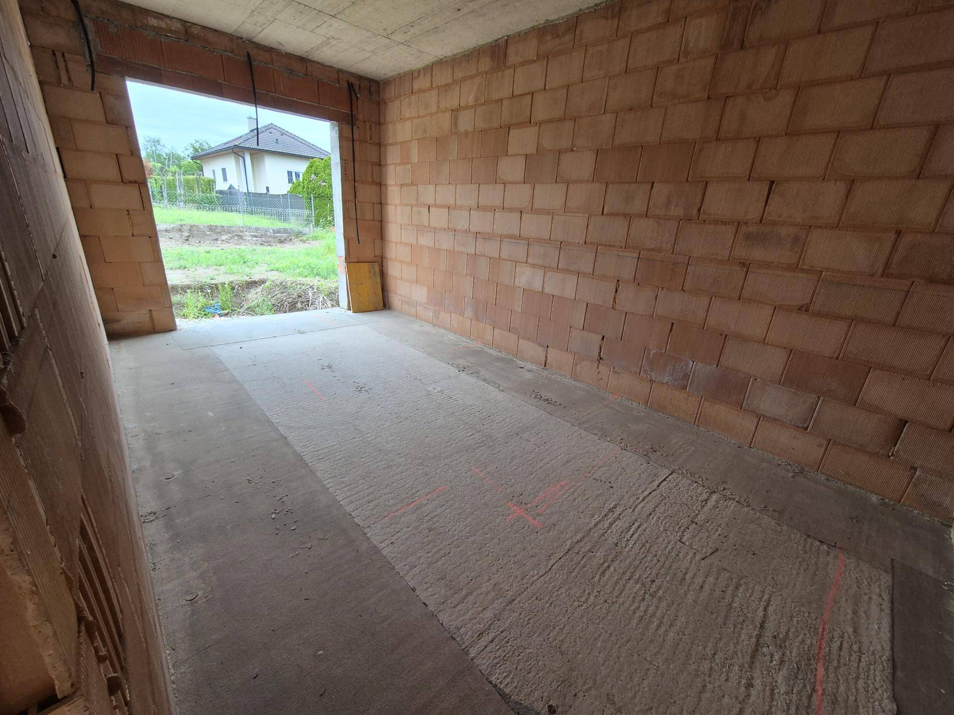 Rohbauzimmer mit Ziegelwänden und großem Durchgang, der einen Blick auf die ländliche Umgebung bietet.