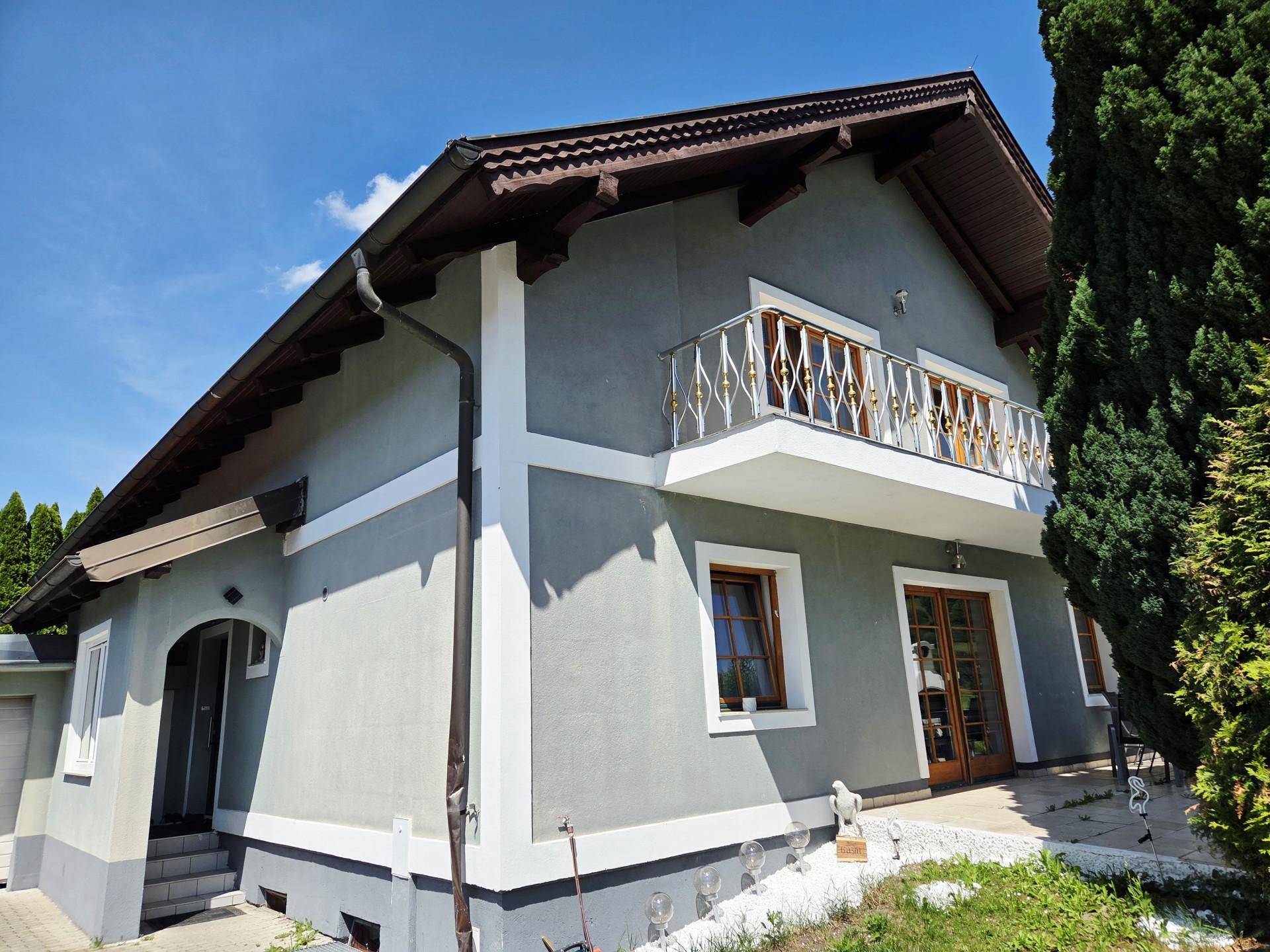 Seitenansicht des Hauses mit Balkon, traditionellem Dachüberstand und gepflegter Fassade.