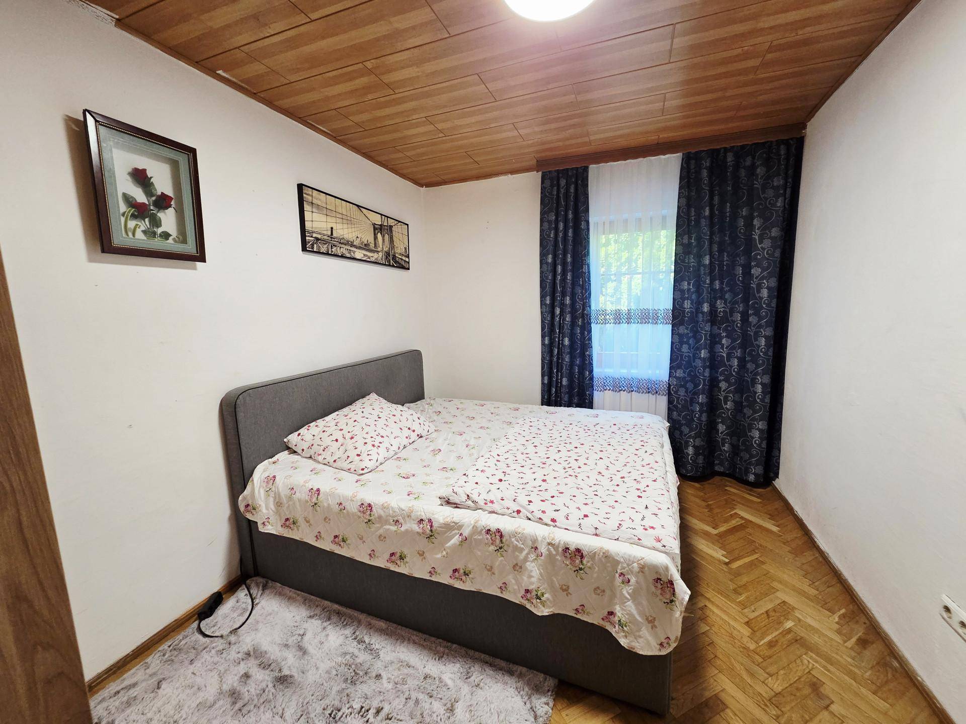Schlafzimmer mit Holzboden, Einzelbett und dunklen Vorhängen, gemütlich eingerichtet.