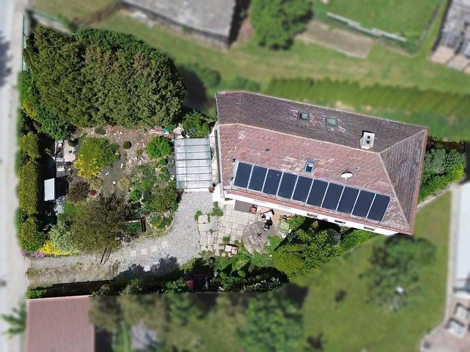 Vogelperspektive des Anwesens mit Solaranlage, großzügigem Garten und gepflasterter Terrasse.