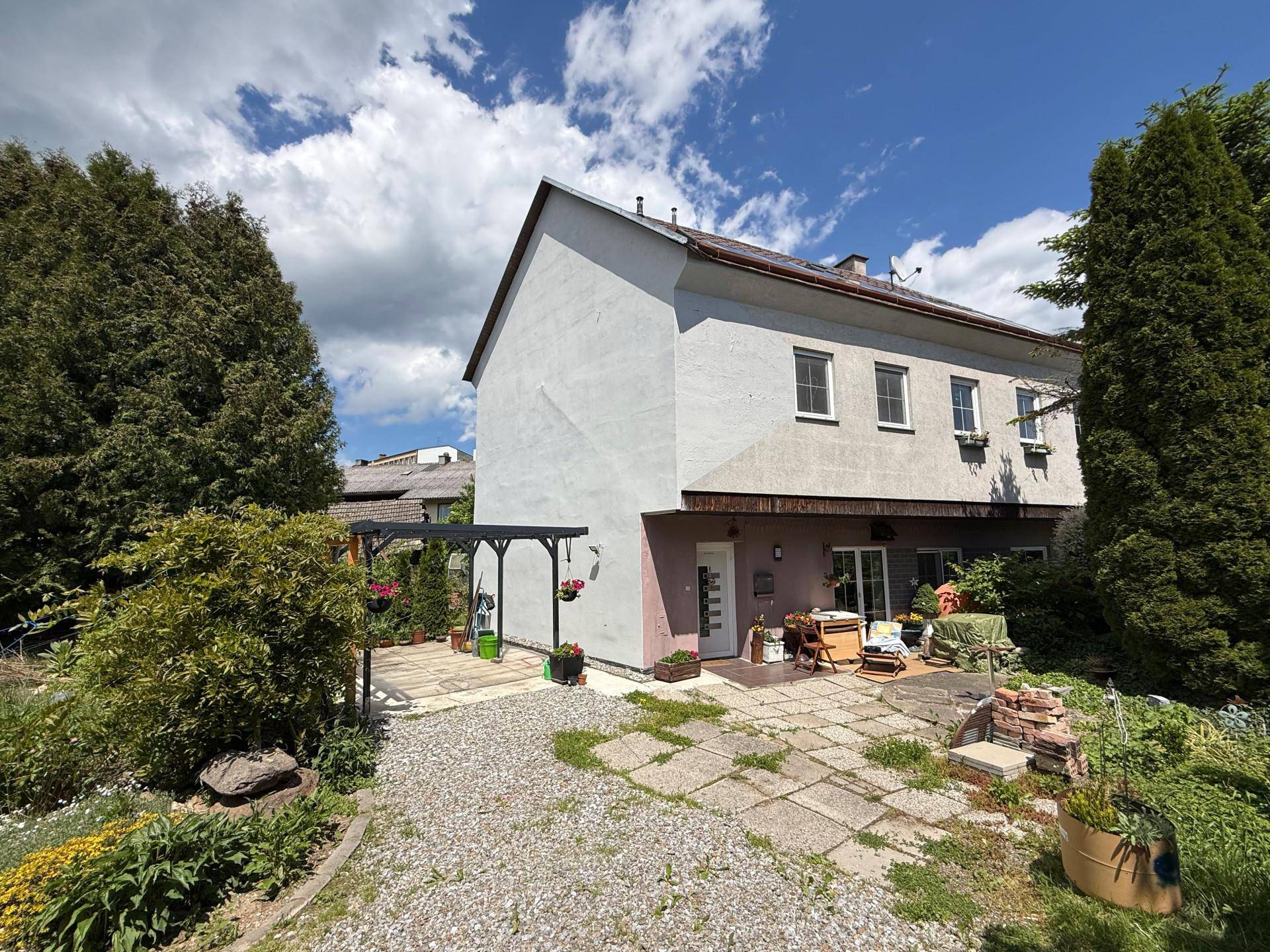 Rückseite des Hauses mit Terrasse, überdachtem Bereich und Zugang zum Garten.