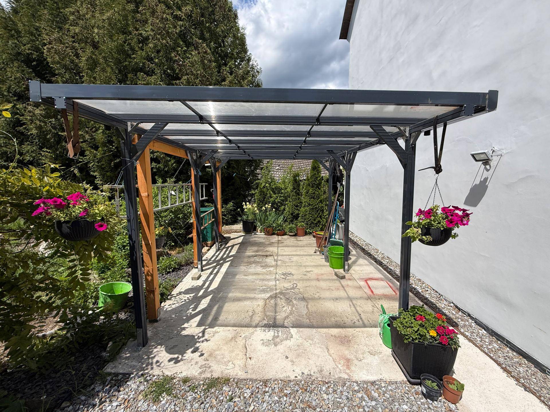 Überdachter Terrassenbereich mit transparentem Dach und hängenden Blumenampeln.